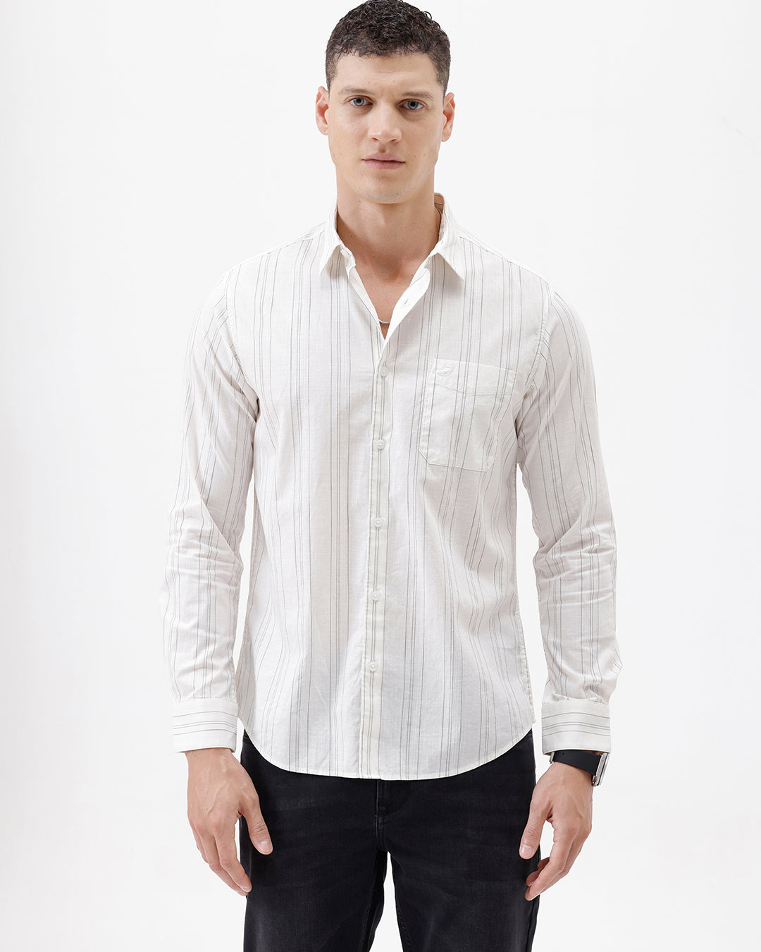 A man wearing a white long-sleeve button-up shirt with thin vertical gray stripes and black pants, standing against a plain white studio background.