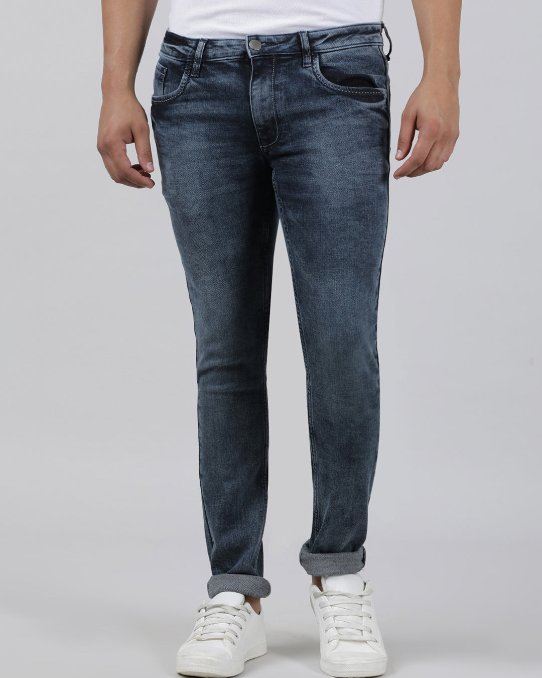 Man wearing a black black and blue solid mid rise slim tapered jean on a light gray background