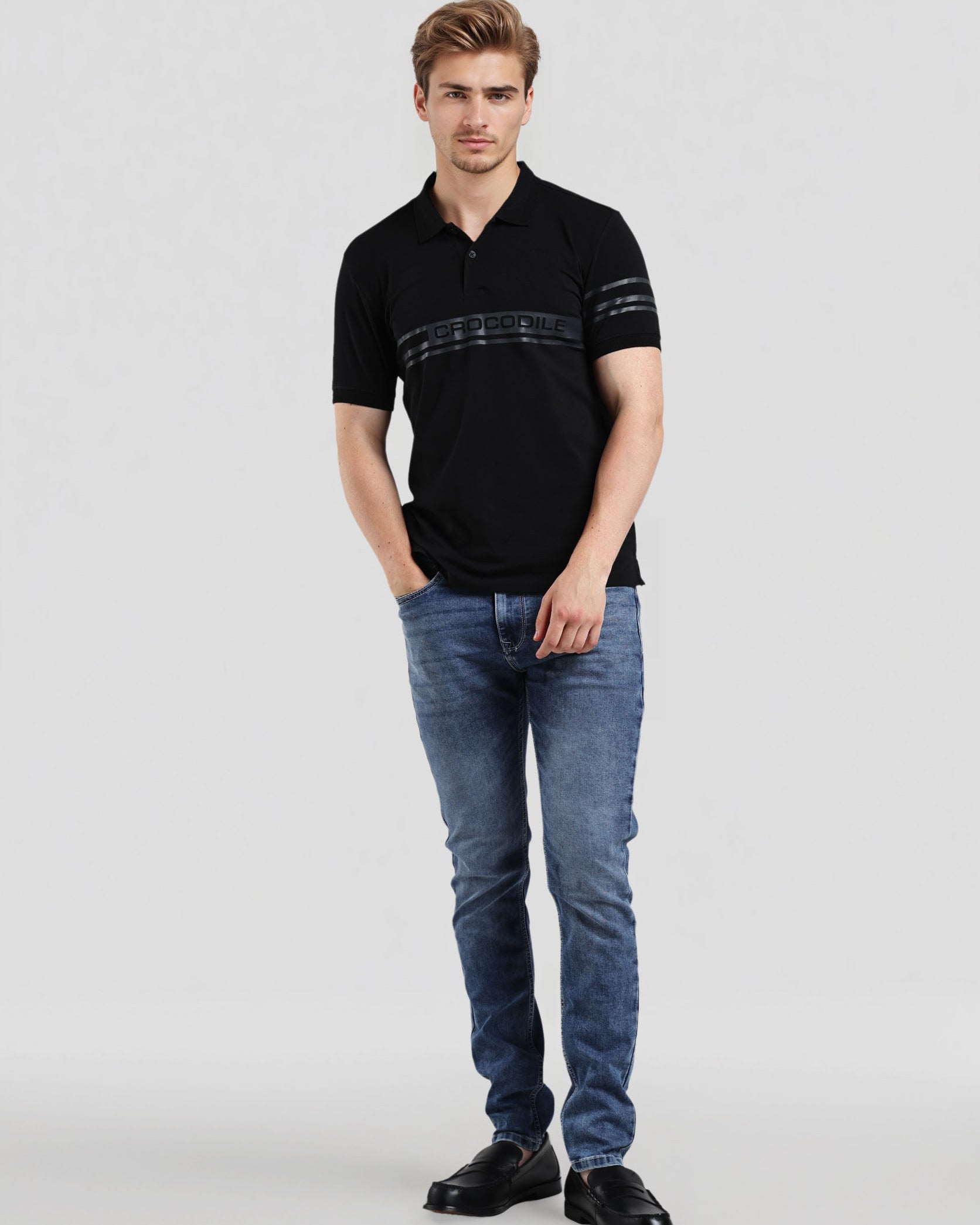 Man wearing a black polo shirt and blue jeans on a white background