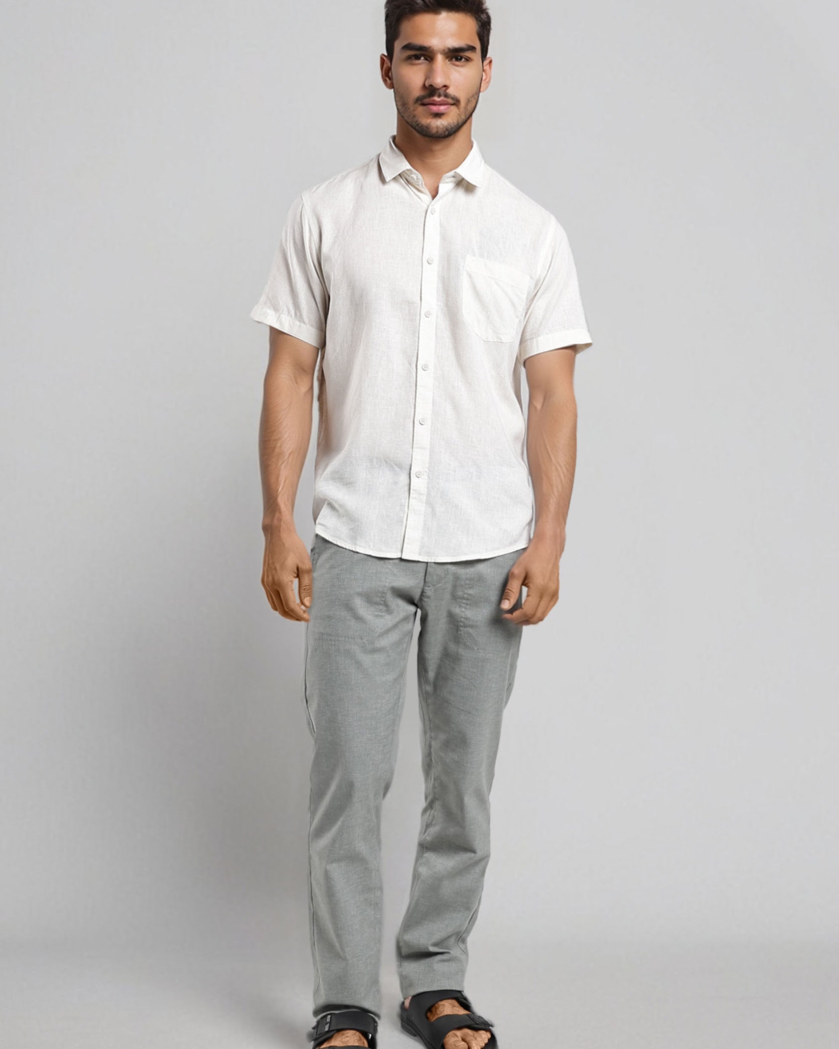Man wearing a white shirt and gray pants on a plain background