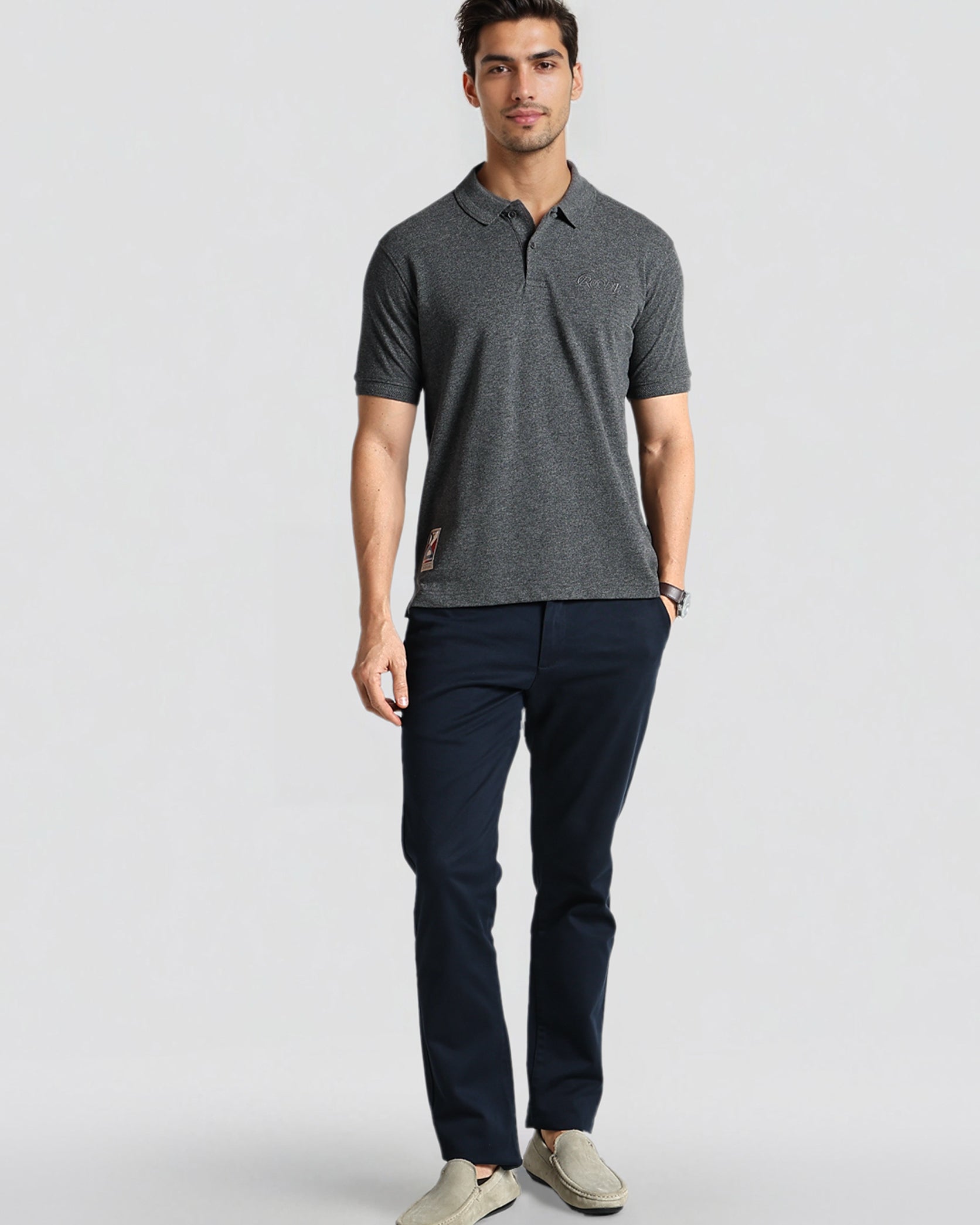 Man wearing a gray polo shirt and navy pants on a light gray background