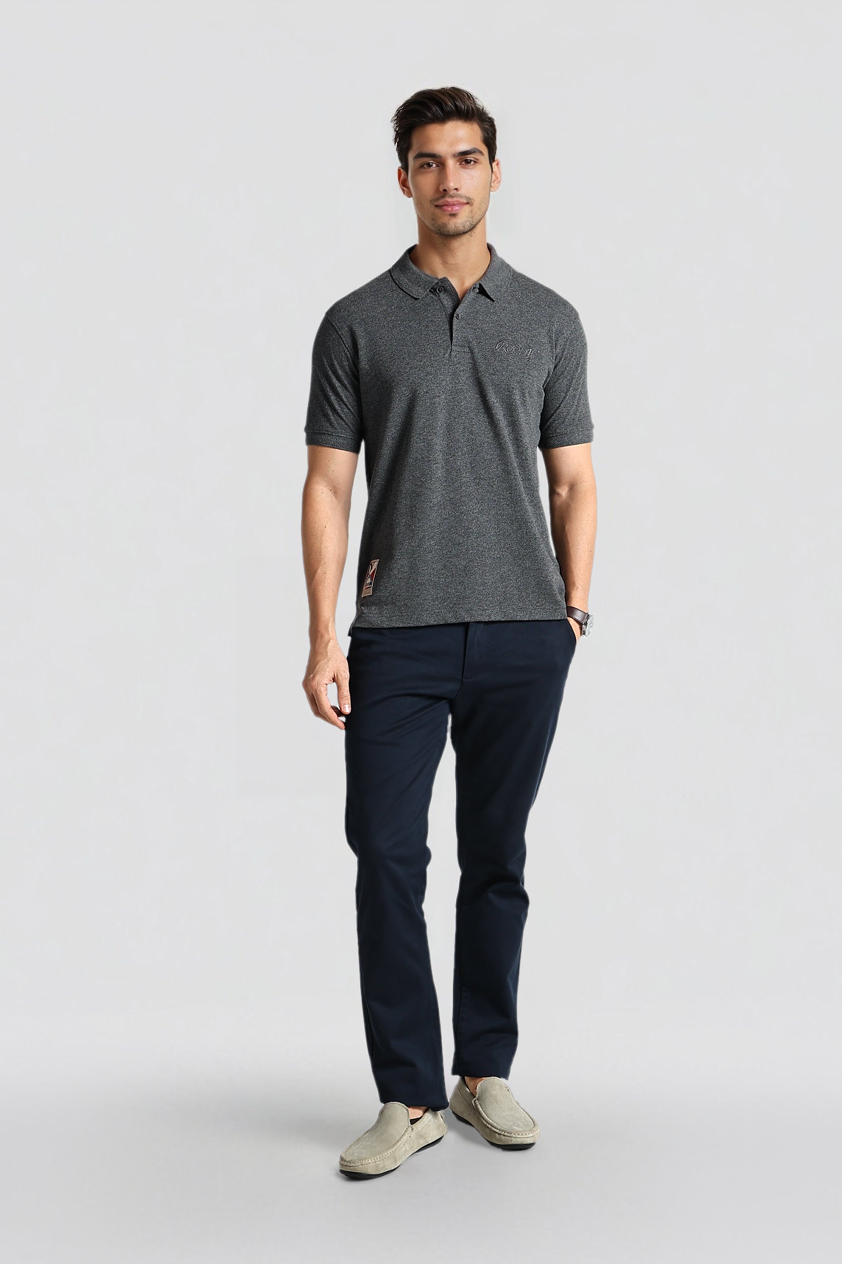 Man wearing a gray polo shirt and navy pants on a light gray background