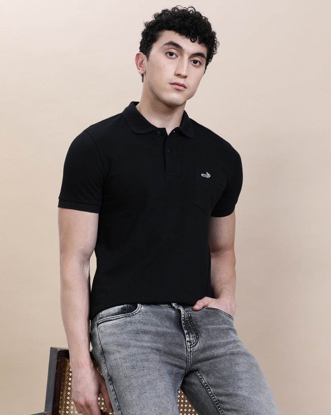 Man wearing a black casual solid black polo t shirt with pocket with casual styling on a gray background