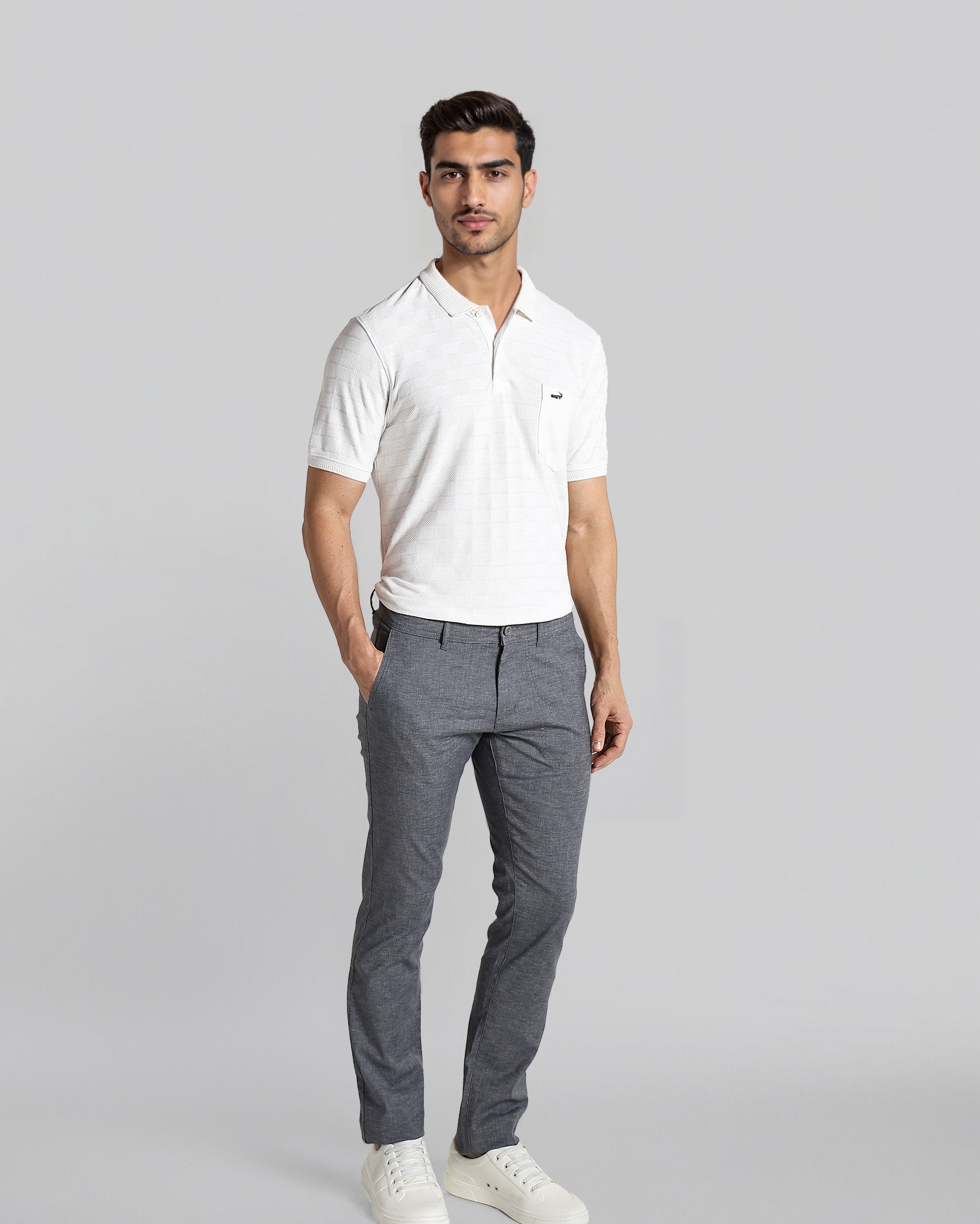 Man wearing a white polo shirt and gray pants on a light gray background