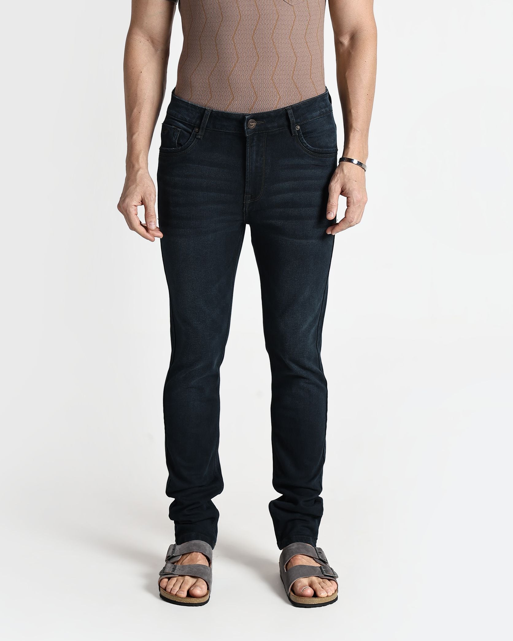 Person wearing dark jeans and a brown shirt on a white background