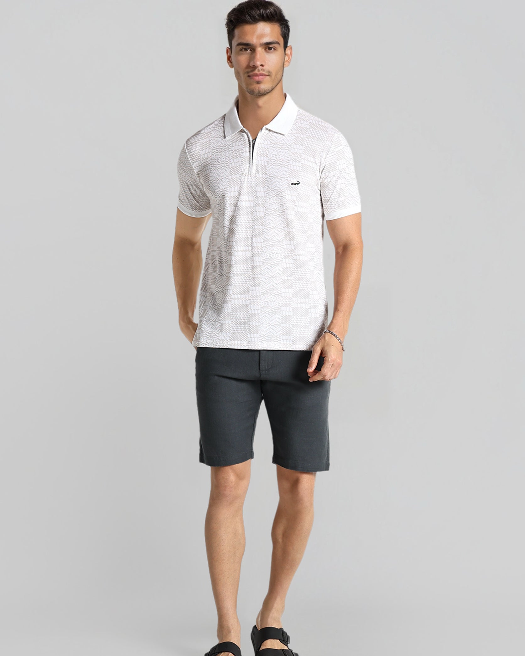 Man wearing a white polo shirt and black shorts on a gray background