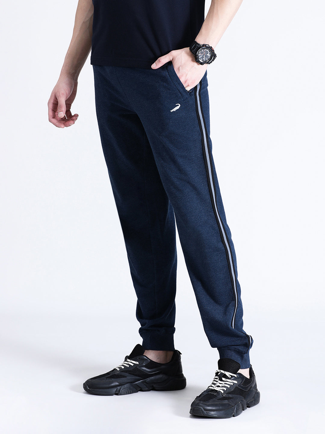 A person standing wearing navy melange joggers with a white stripe on the side, a black top, and black sneakers.