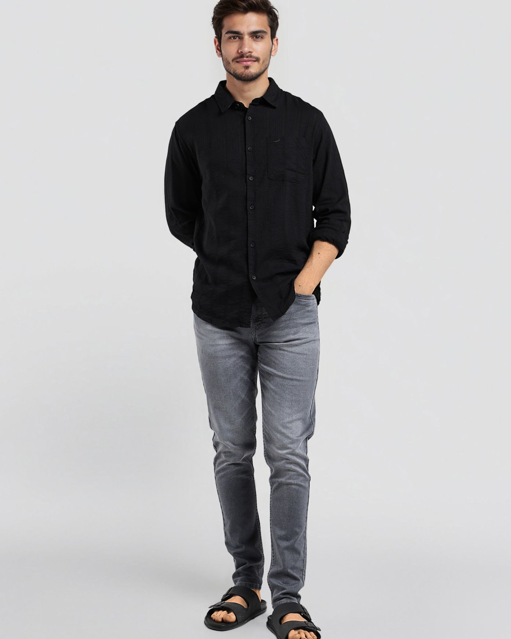 Man wearing a black shirt and gray jeans on a white background
