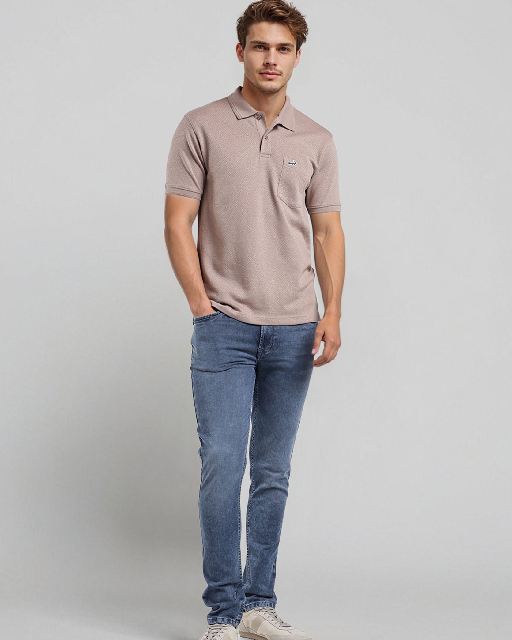 Man wearing a beige polo shirt and blue jeans on a light gray background