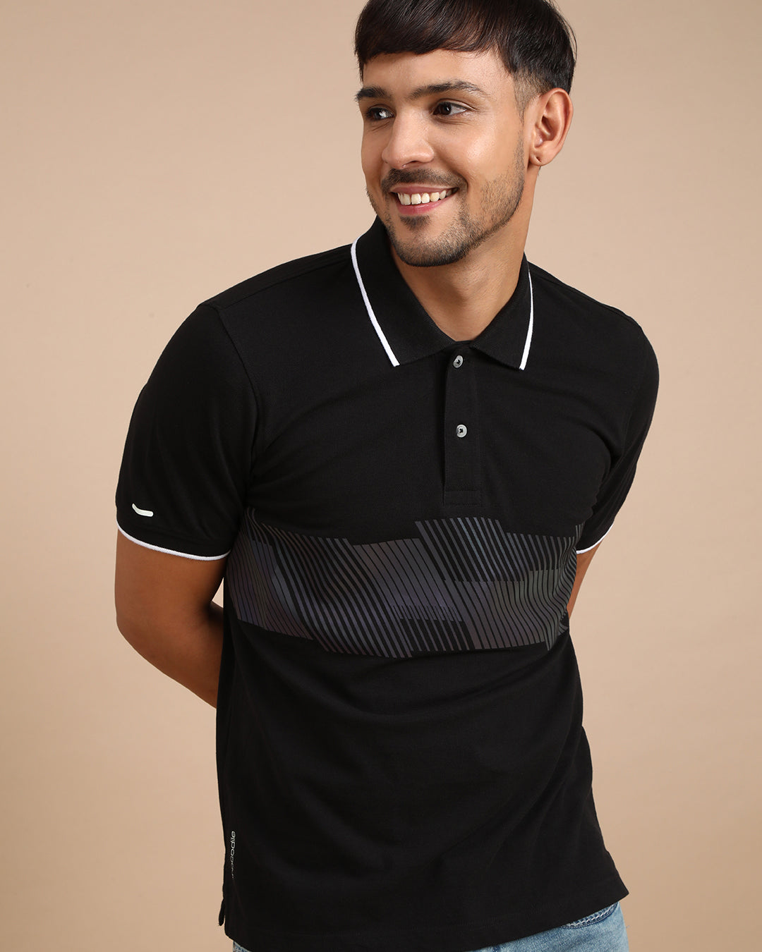 Man wearing a black black casual printed polo t shirt on a light gray background