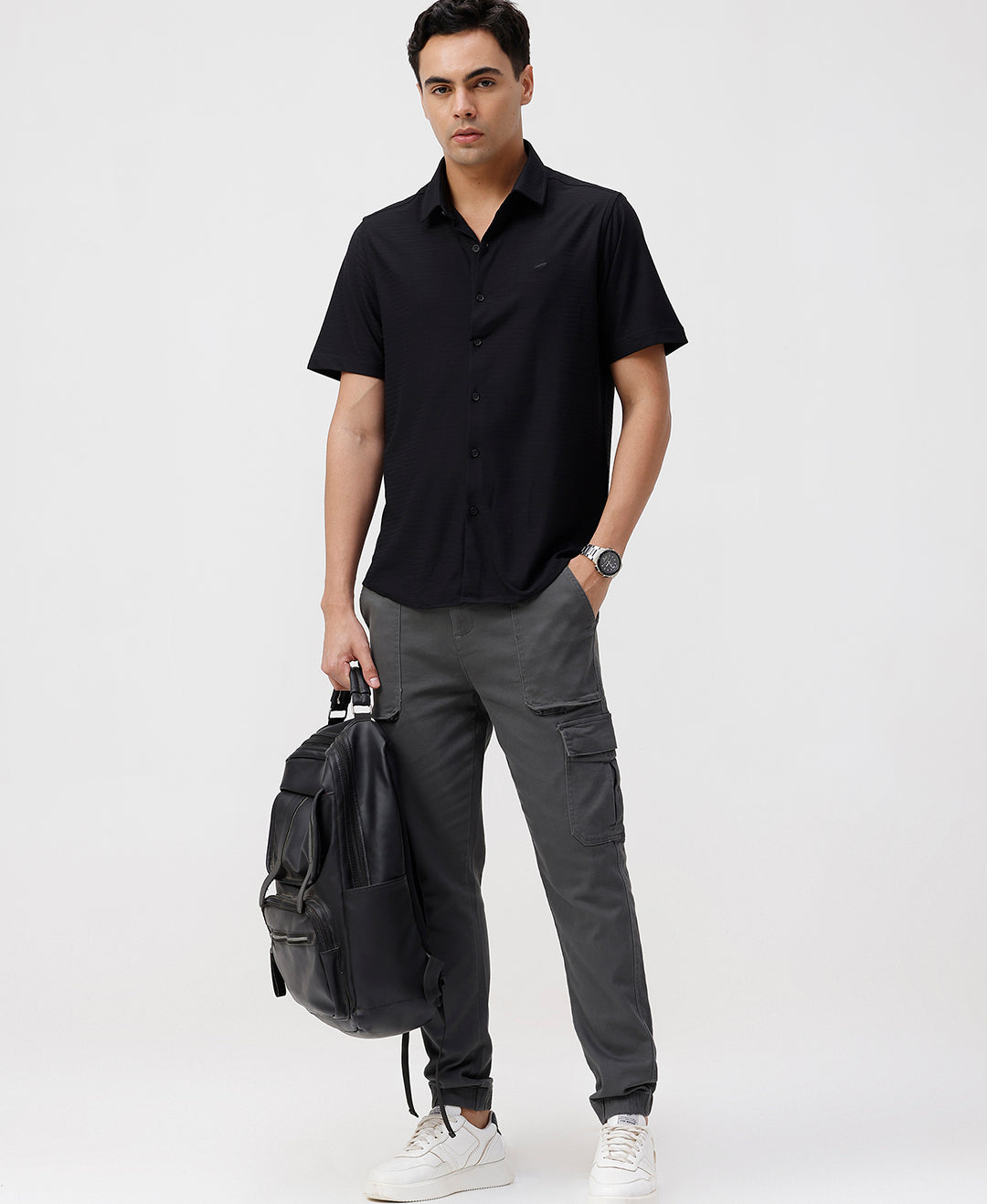 Man wearing a black solid black cotton shirt with casual styling on a gray background