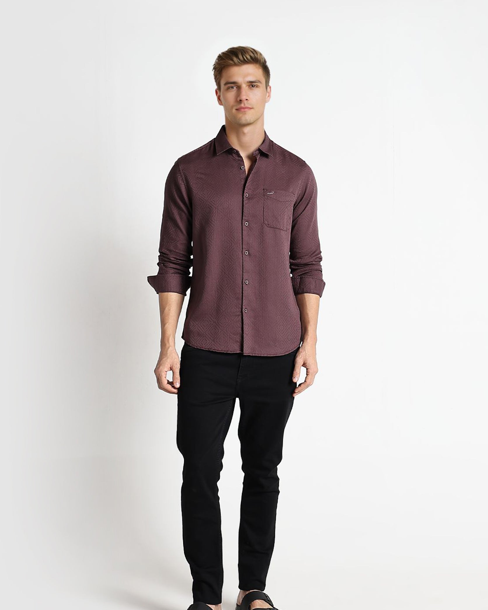 Man wearing a brown button-up shirt and black pants on a white background