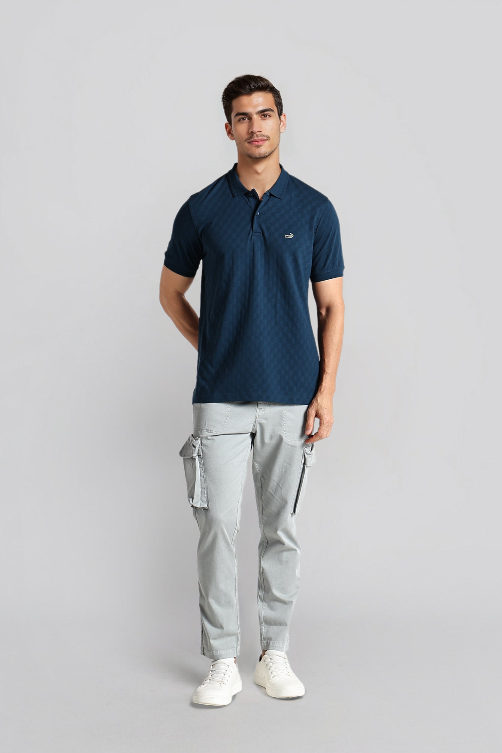 Man wearing a navy polo shirt and gray cargo pants on a light gray background