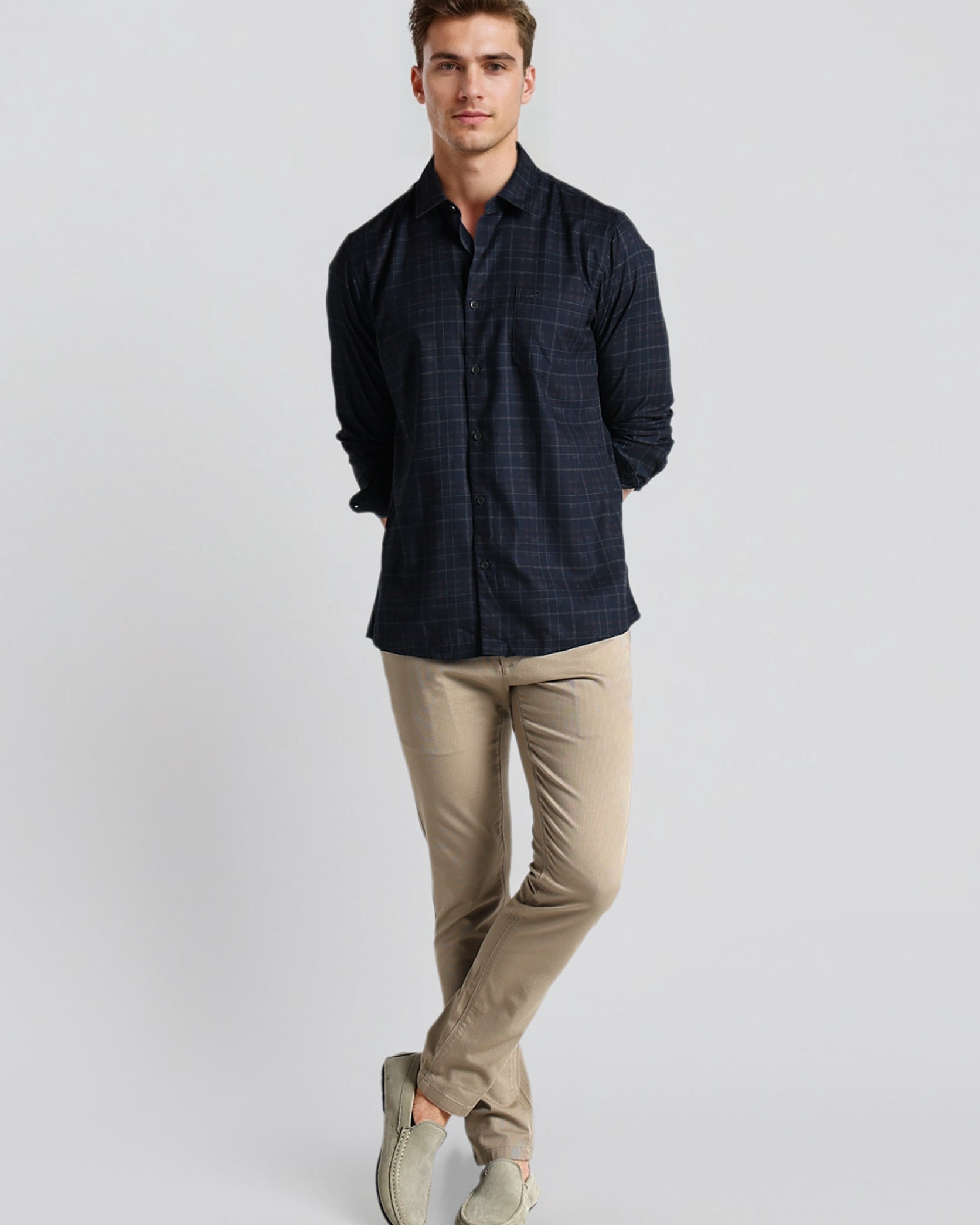 Man wearing a dark shirt and beige pants on a light gray background