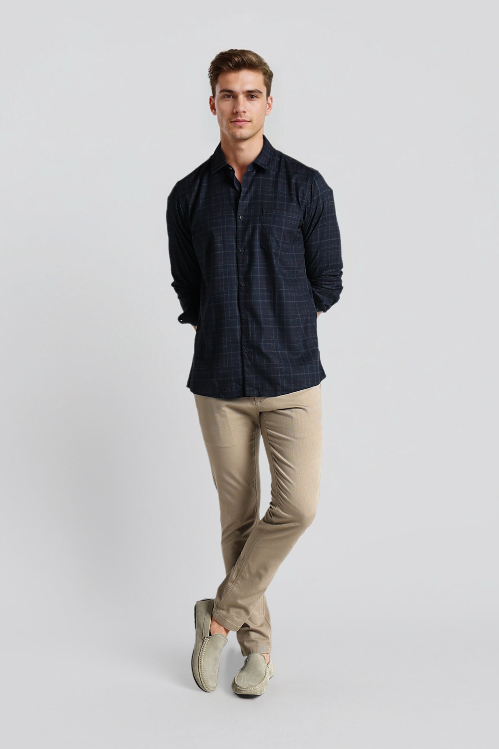 Man wearing a dark shirt and beige pants on a light gray background