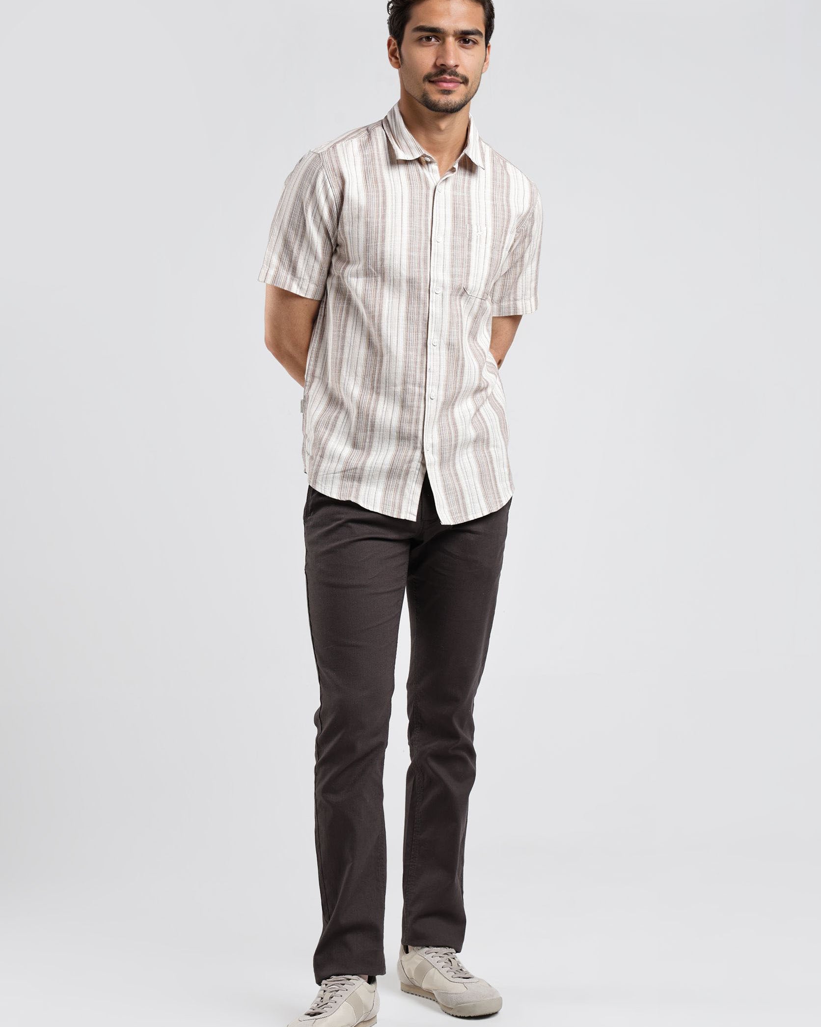 Man wearing a striped shirt and dark pants on a white background