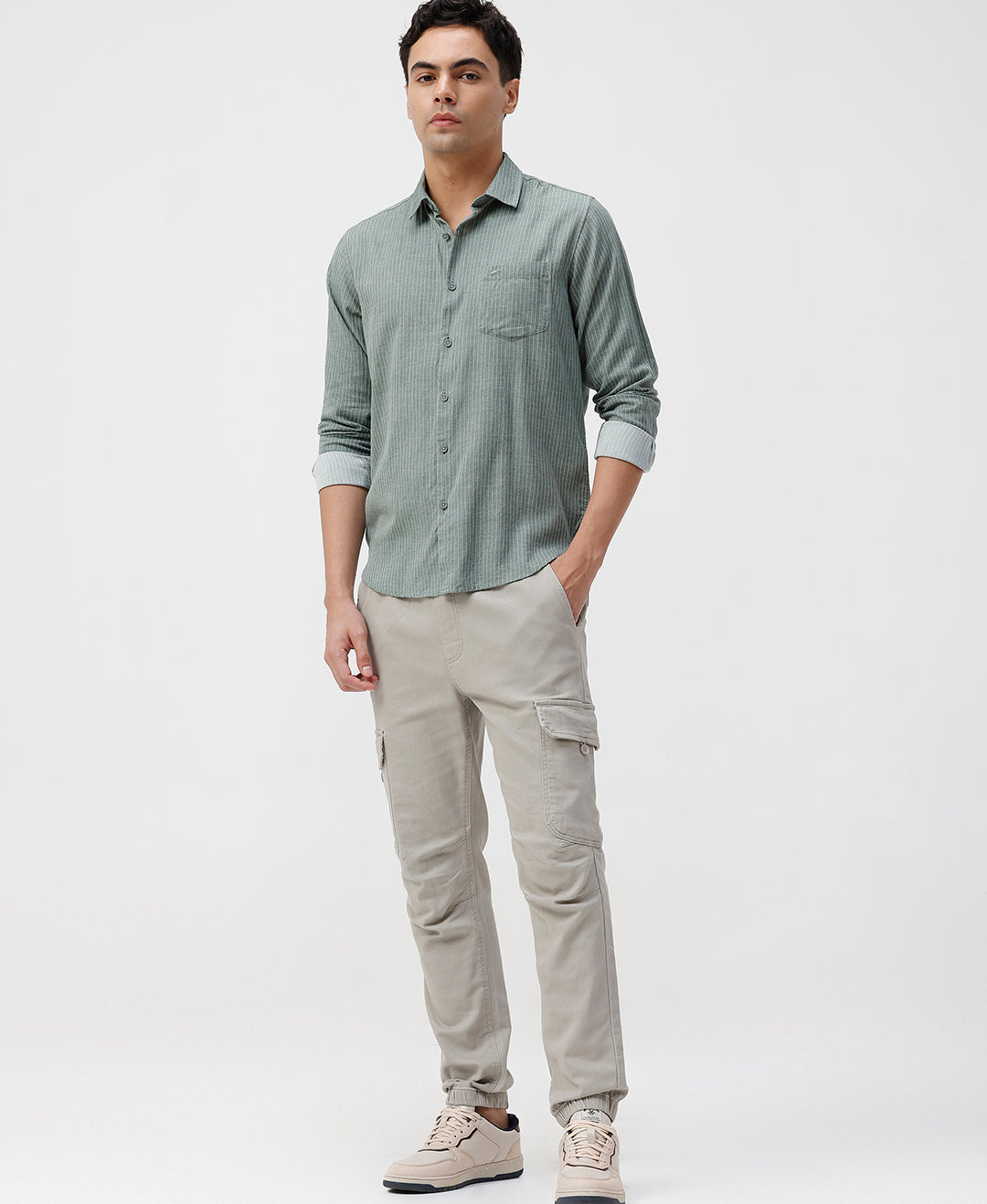Man wearing a light green shirt and beige pants on a white background