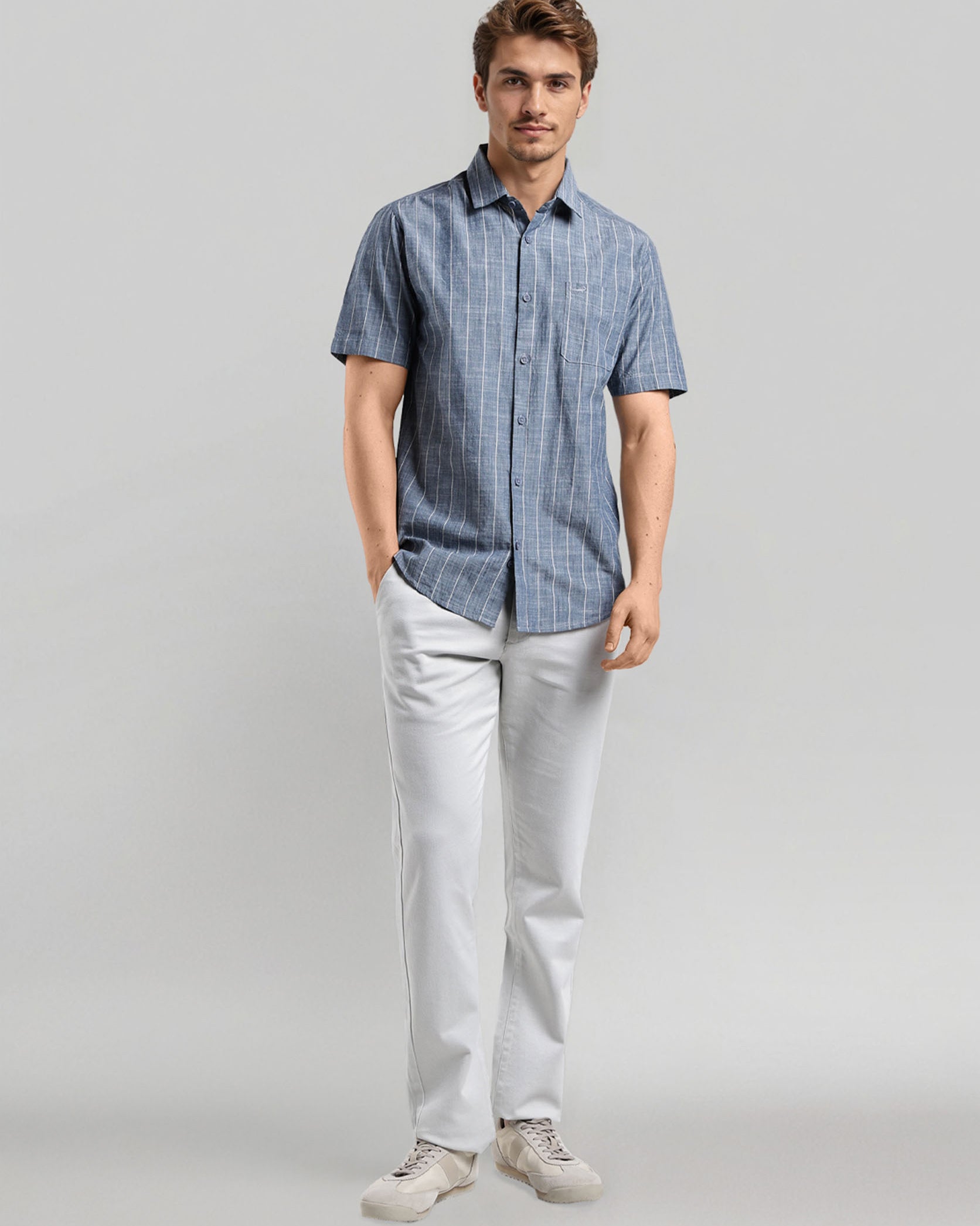 Man wearing a blue checkered shirt and white pants on a gray background