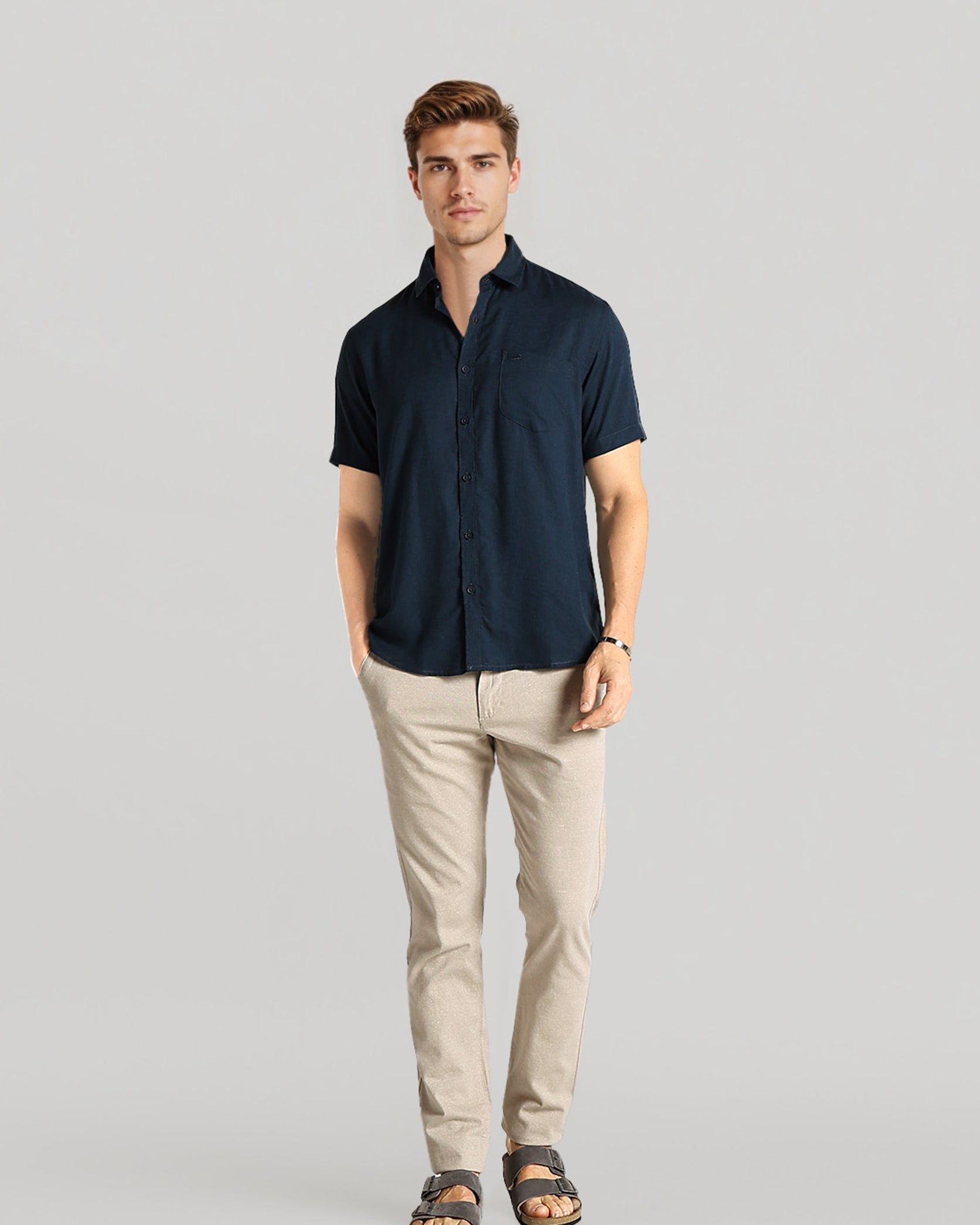 Man wearing a navy shirt and beige pants on a gray background