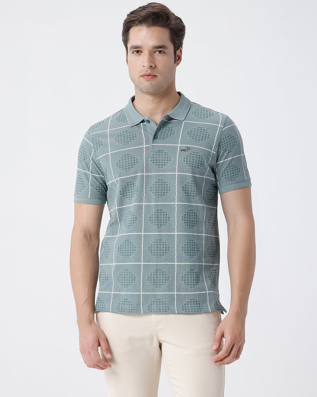 Man wearing a green checkered all over printed polo t shirt green with casual styling on a gray background