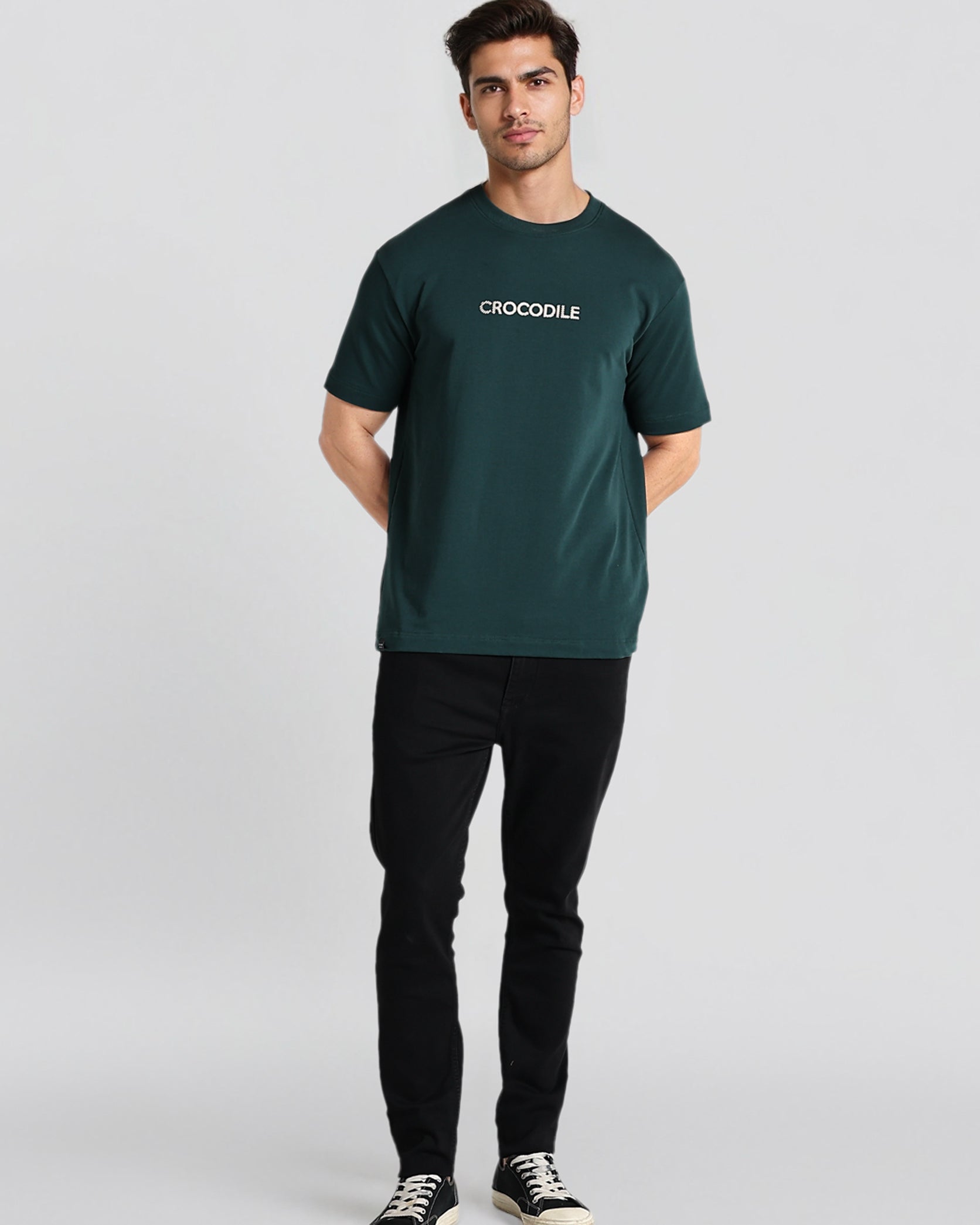 Man wearing a green t-shirt with 'CROODLE' logo on a light gray background