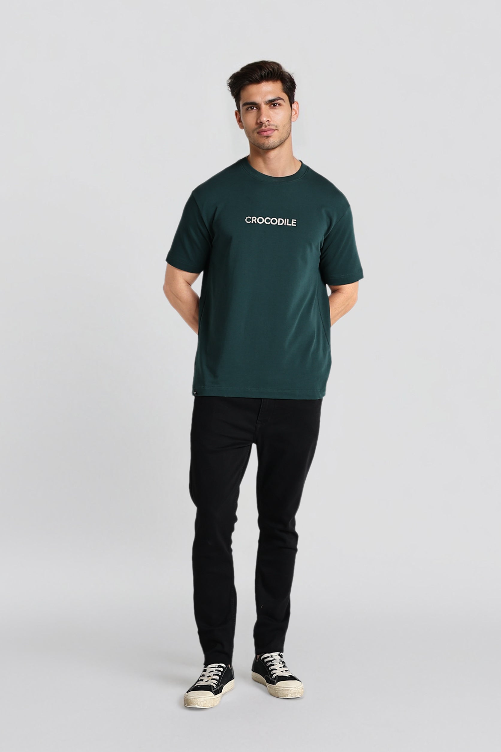 Man wearing a green t-shirt with 'CROODLE' logo on a light gray background