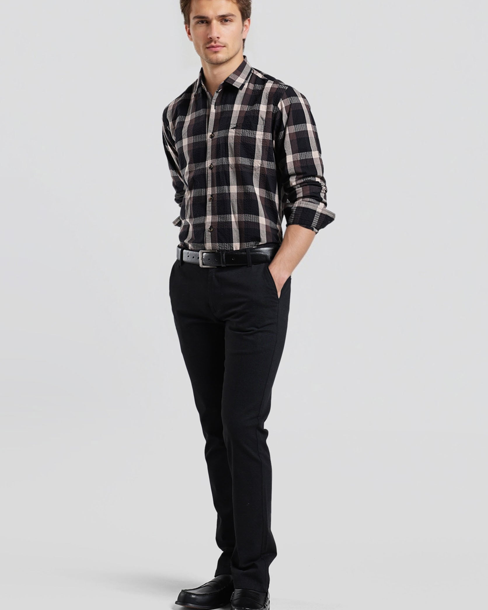 Man wearing a plaid shirt and black pants on a white background