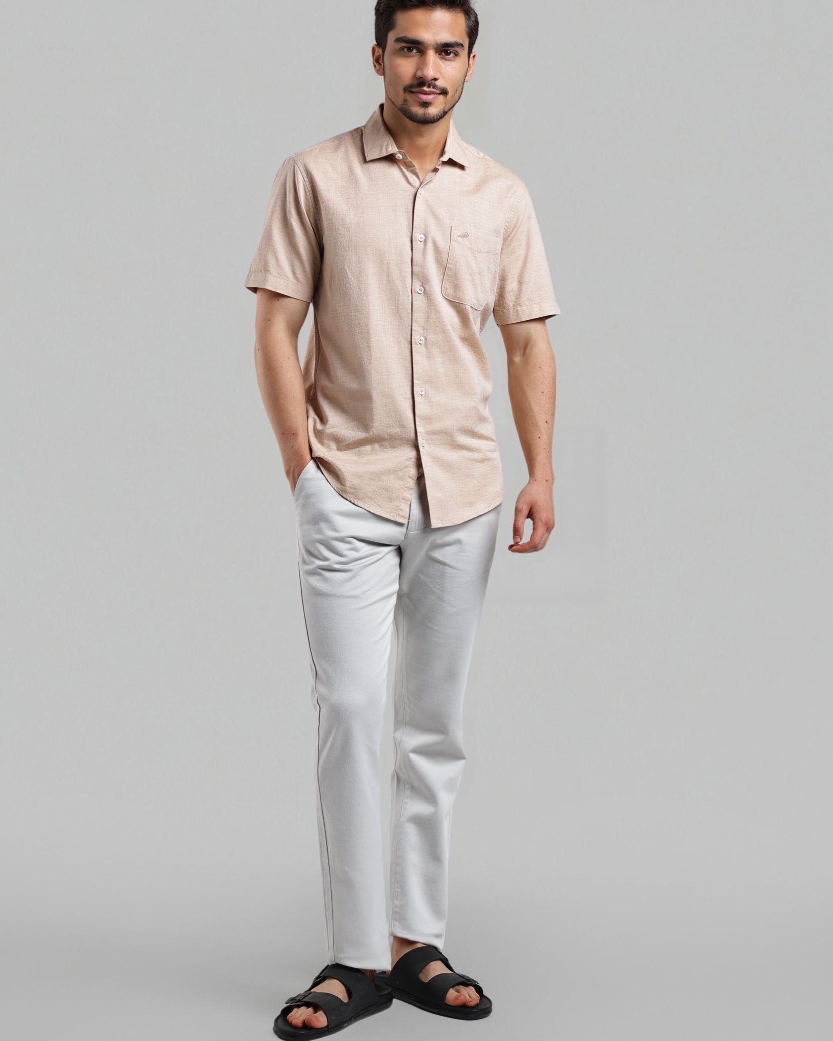 Man wearing a beige shirt and white pants on a gray background