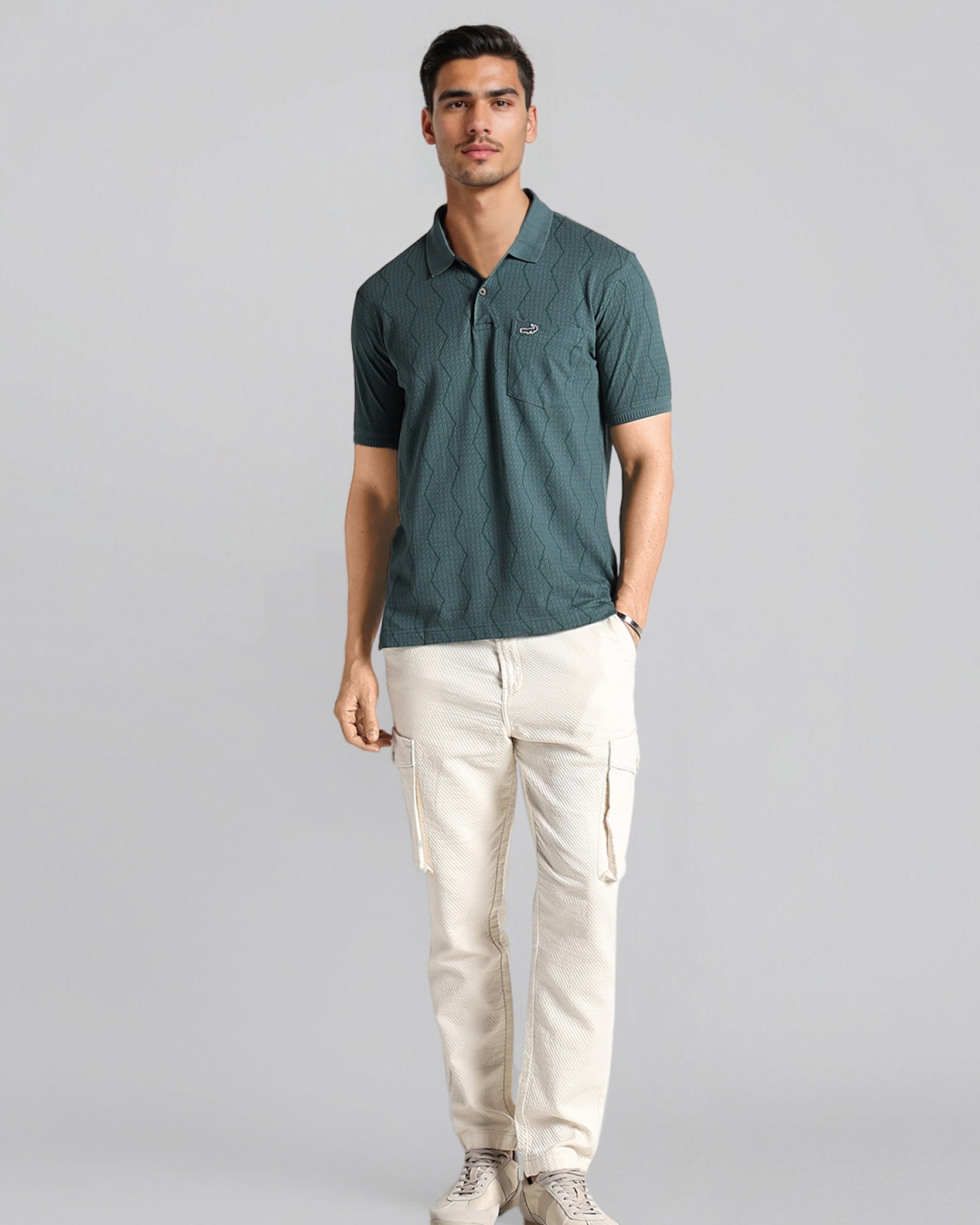 Man wearing a green polo shirt and white pants on a gray background