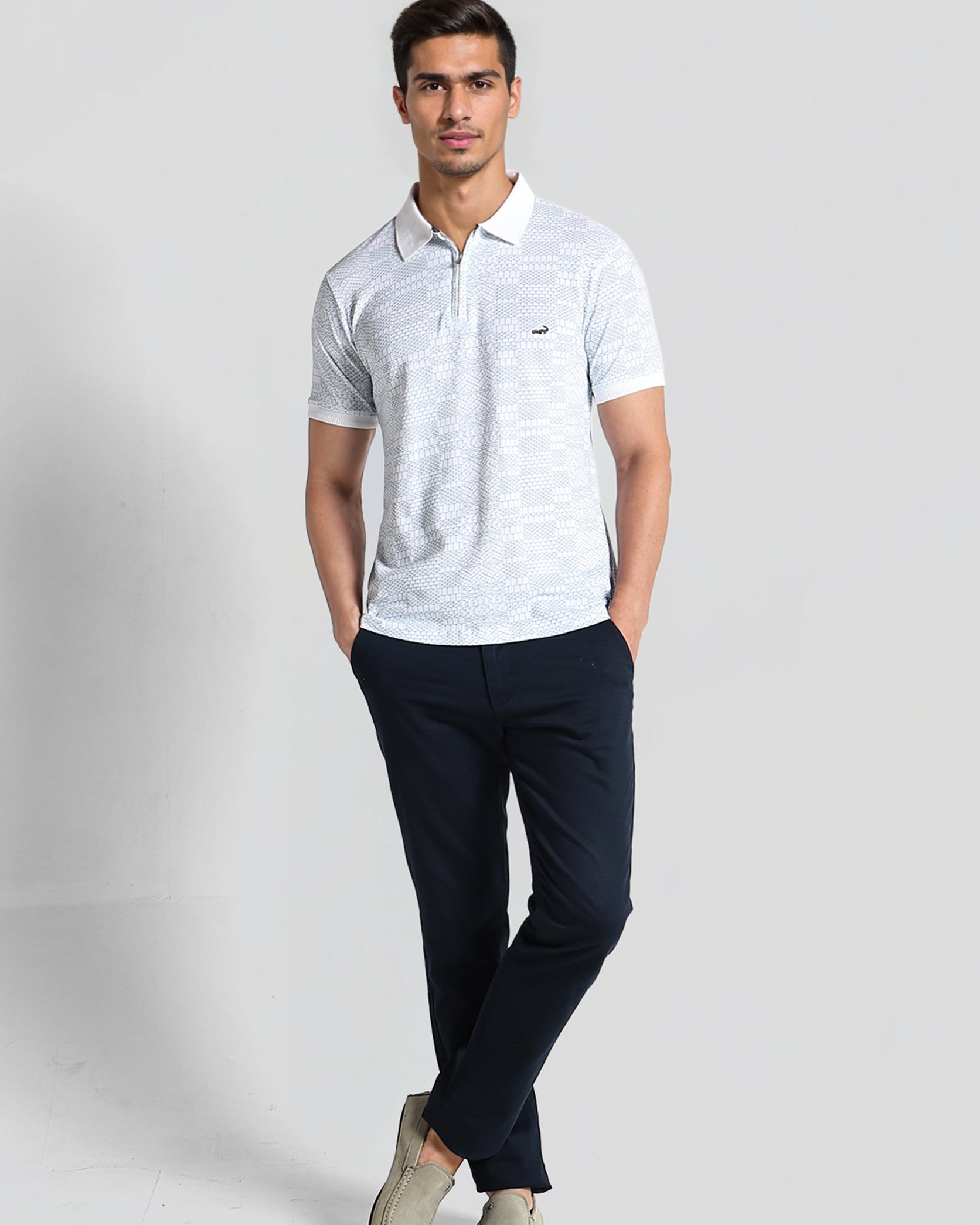 Man wearing a light gray polo shirt and dark blue pants on a white background