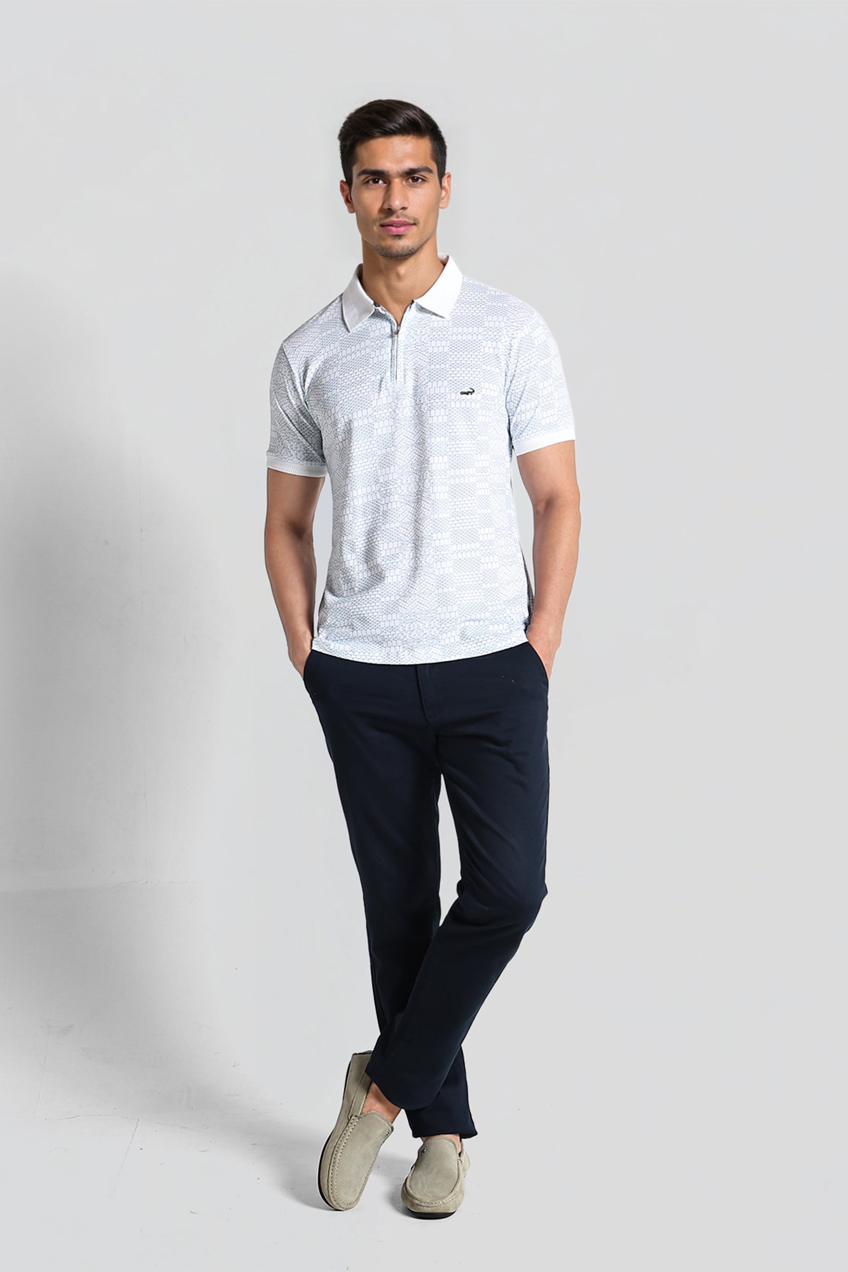 Man wearing a light gray polo shirt and dark blue pants on a white background