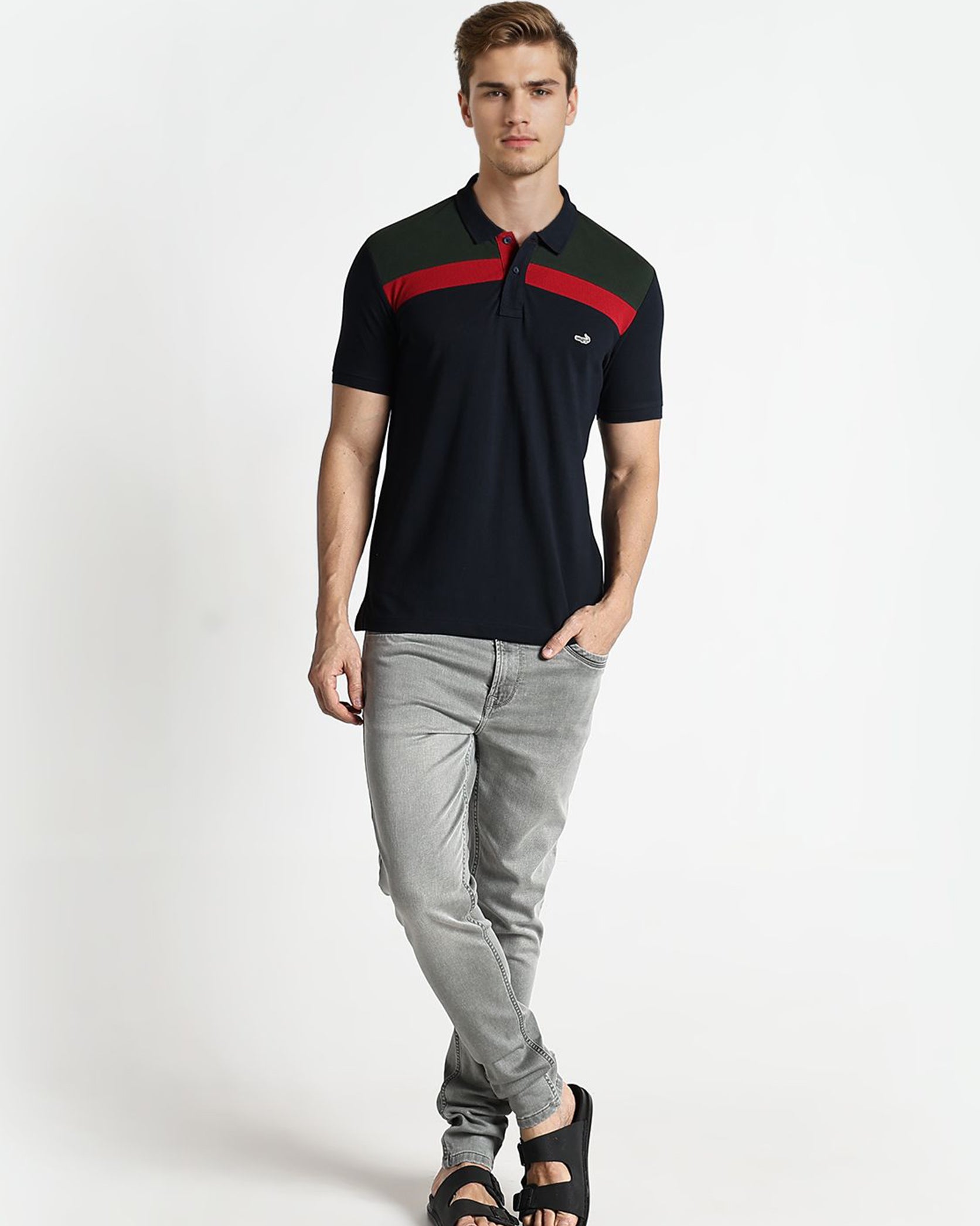 Man wearing a black and red polo shirt with gray pants on a white background