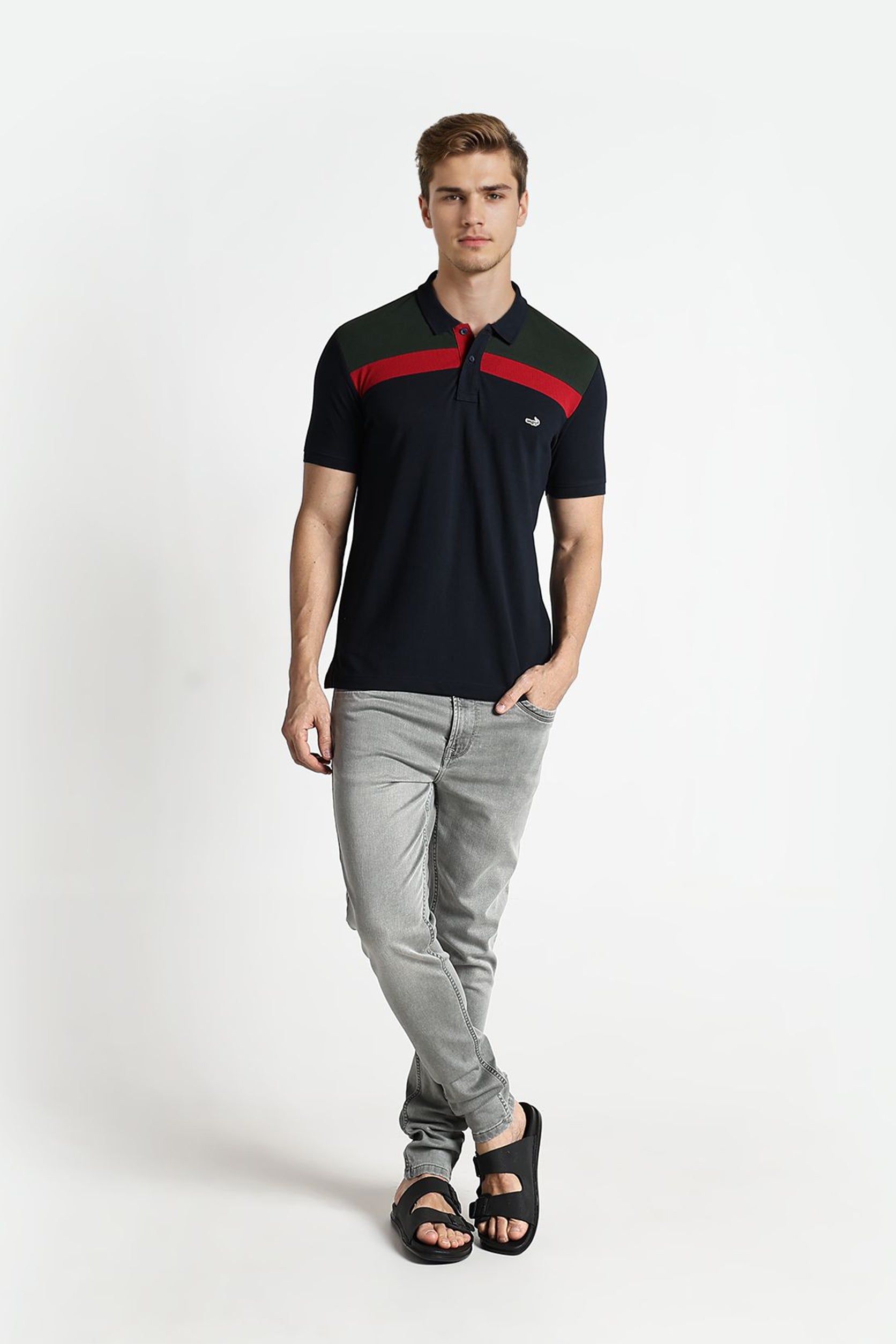 Man wearing a black and red polo shirt with gray pants on a white background