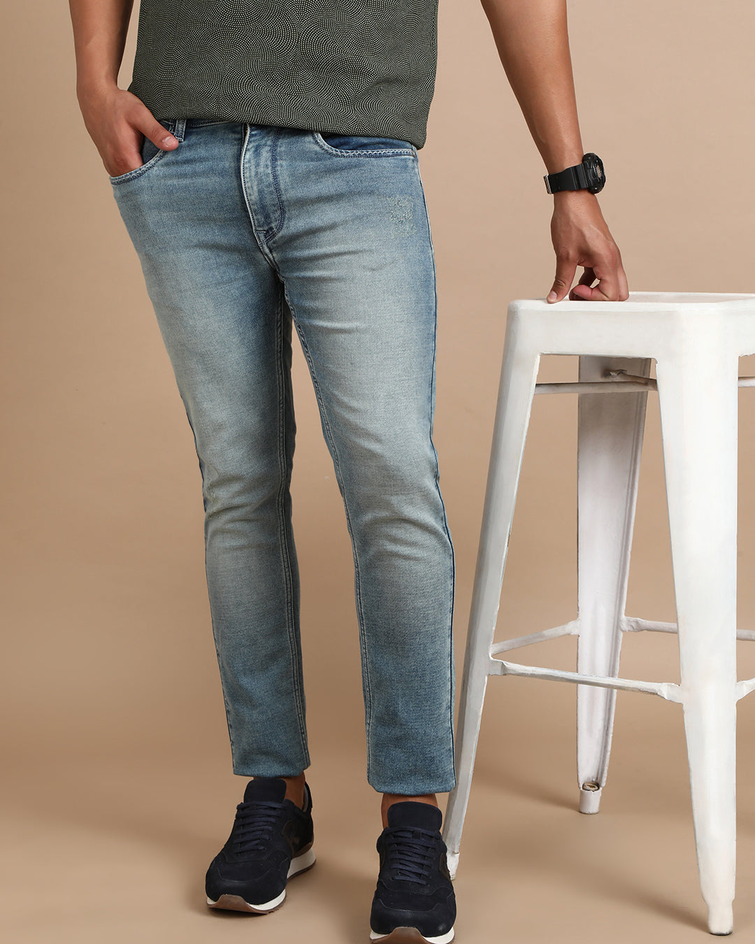 Man wearing a blue light blue solid mid rise slim fit jean with casual styling on a gray background