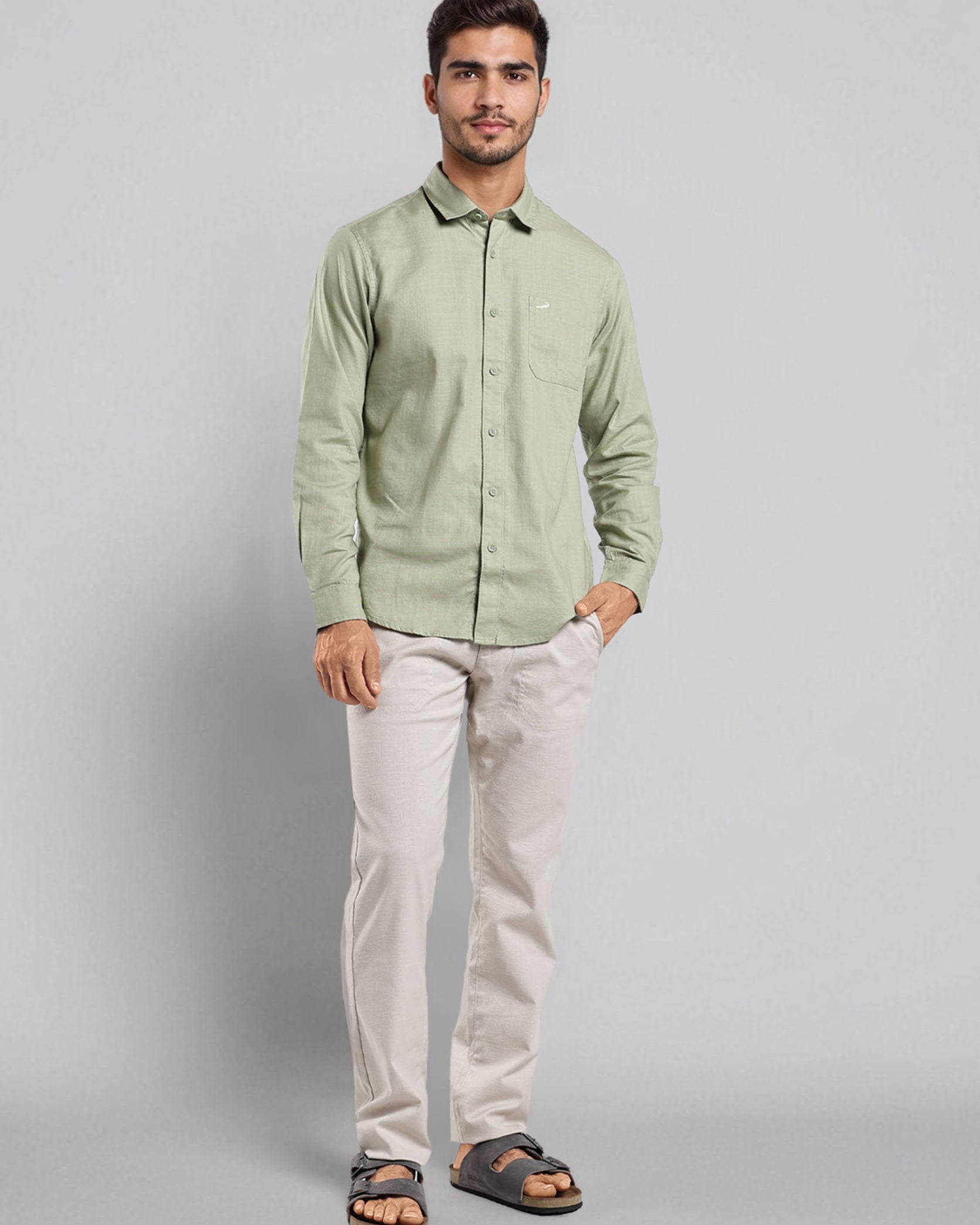 Man wearing a light green shirt and white pants on a gray background