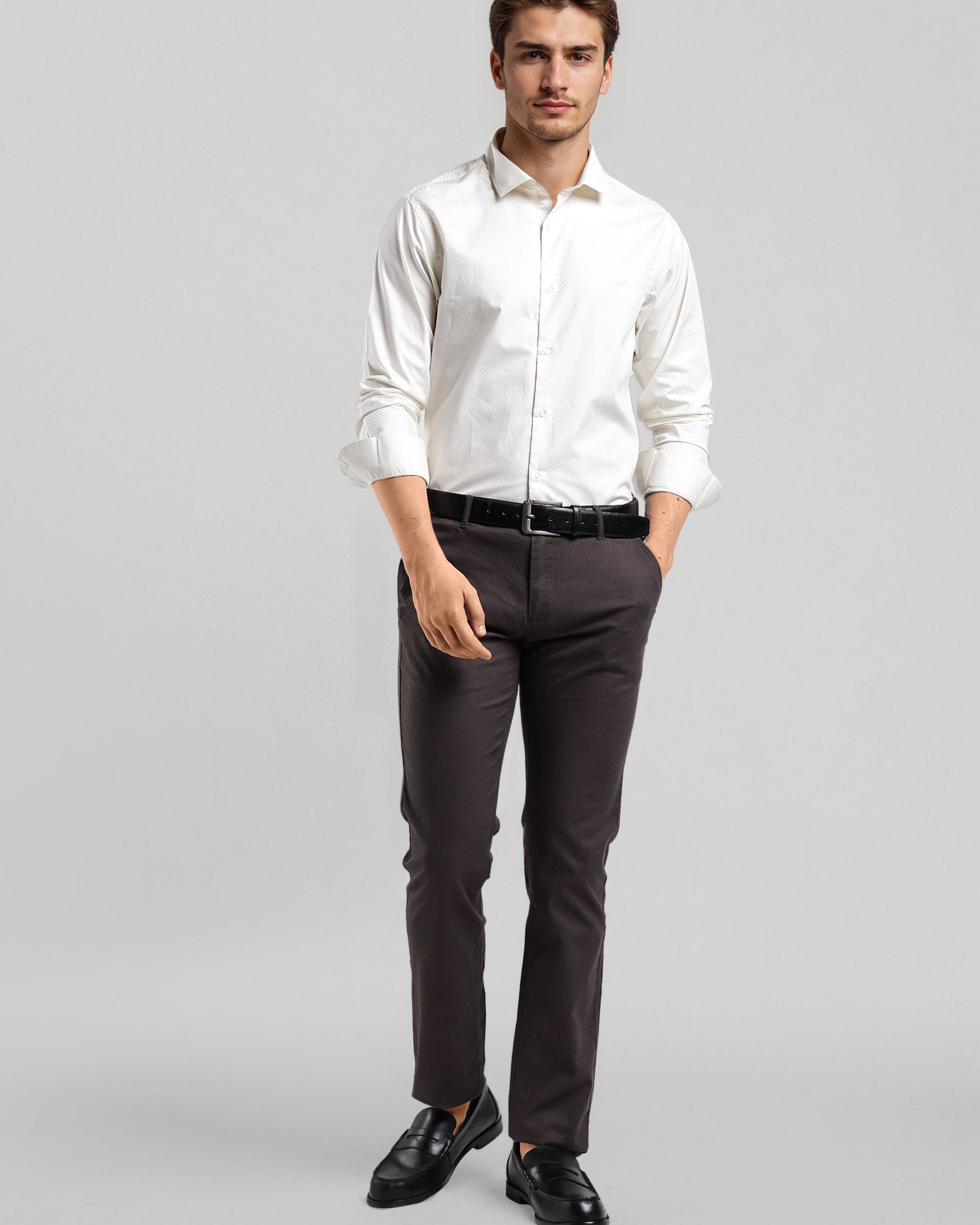 Man wearing a white dress shirt, dark pants, and black shoes on a gray background