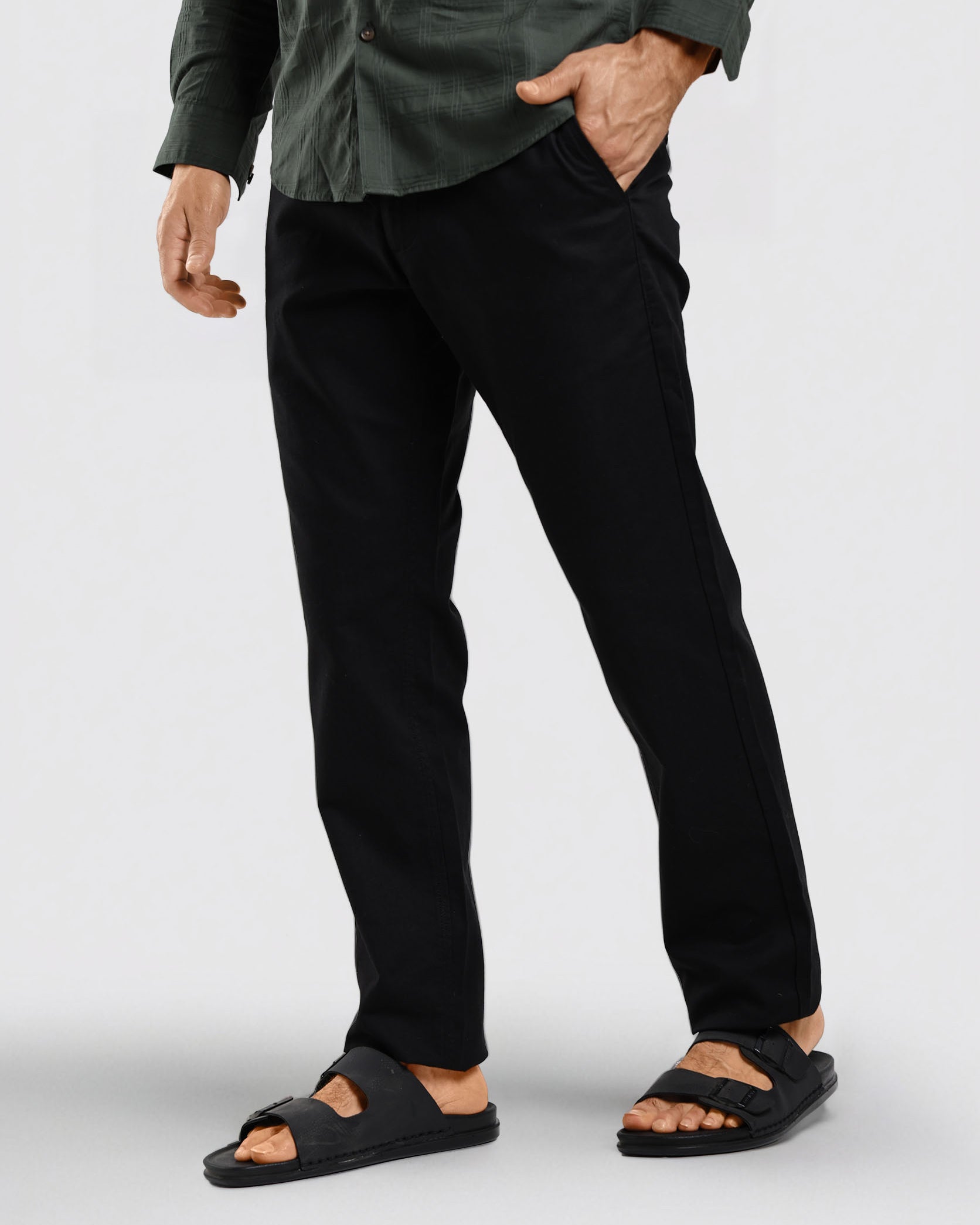 Person wearing black pants and sandals on a white background