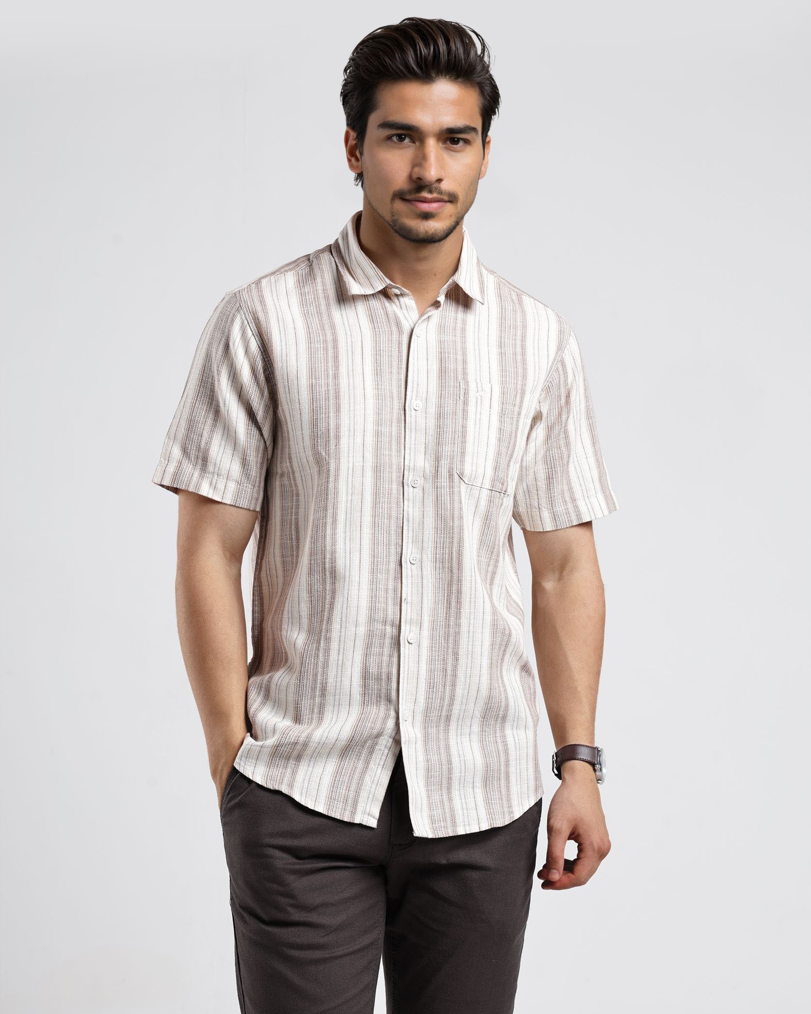 Man wearing a striped shirt and dark pants on a white background