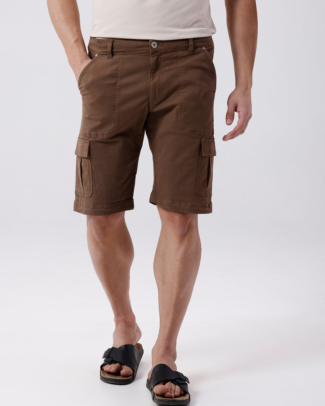 Man wearing a brown garment dyed cargo shorts in brown on a light gray background