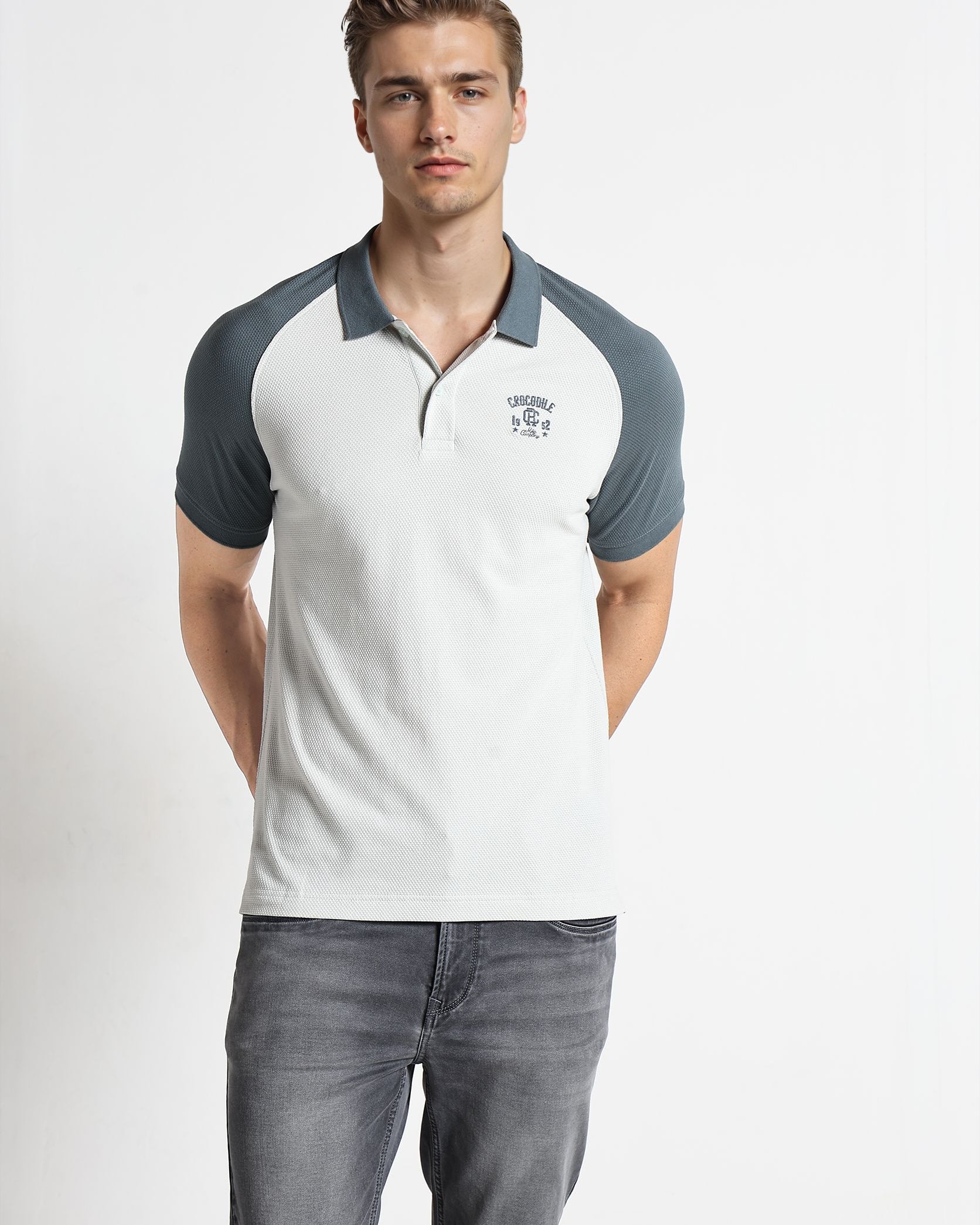 Man wearing a gray and white polo shirt with a logo on a white background