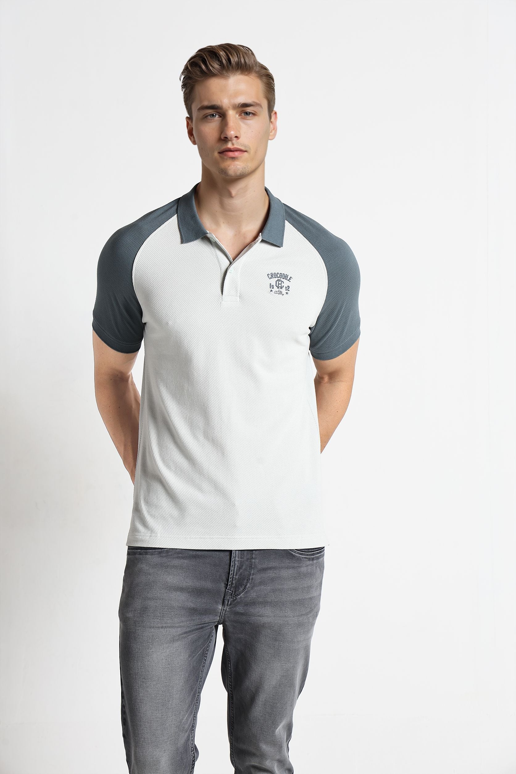 Man wearing a gray and white polo shirt with a logo on a white background