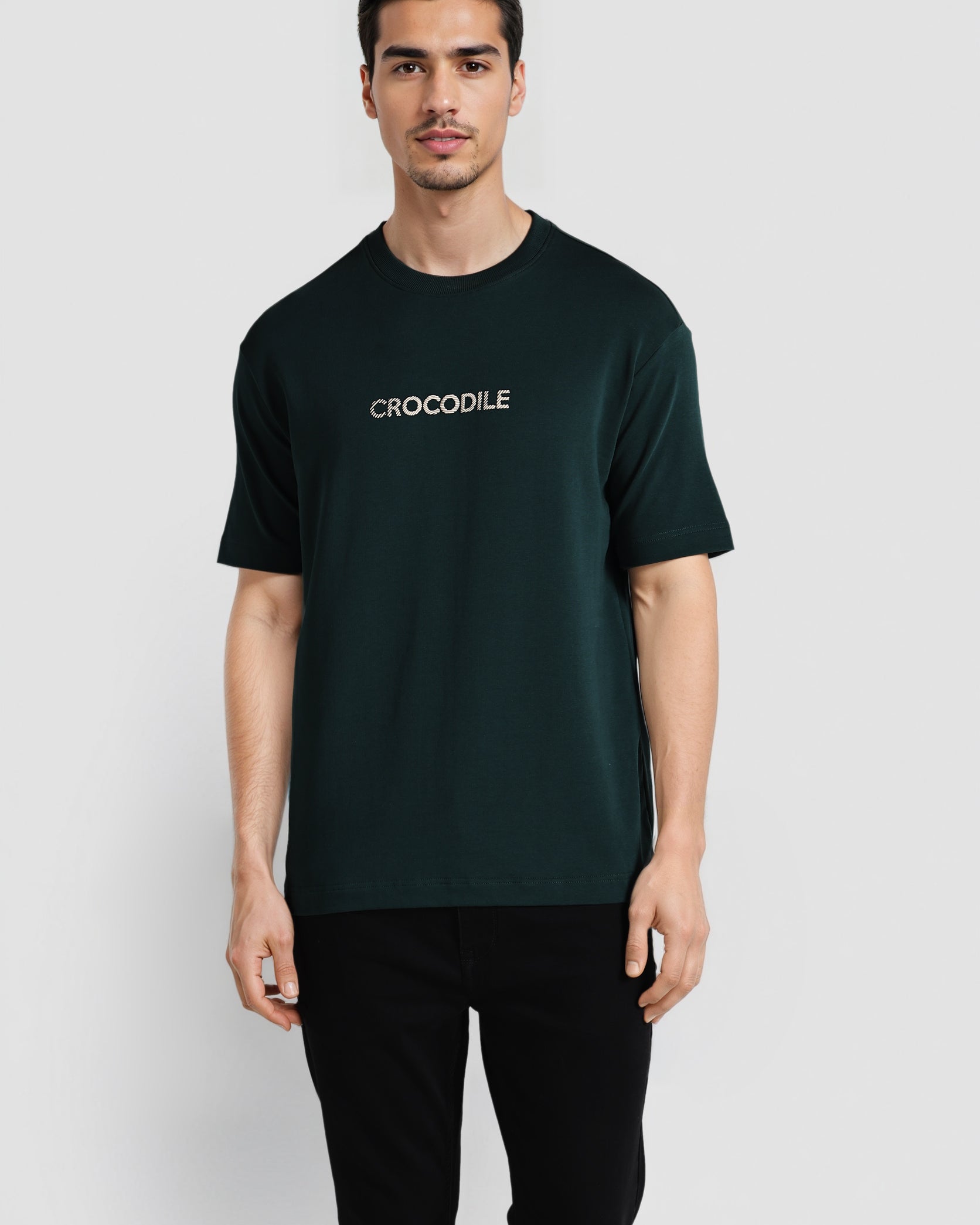 Man wearing a dark green t-shirt with 'CROCODILE' logo on a white background