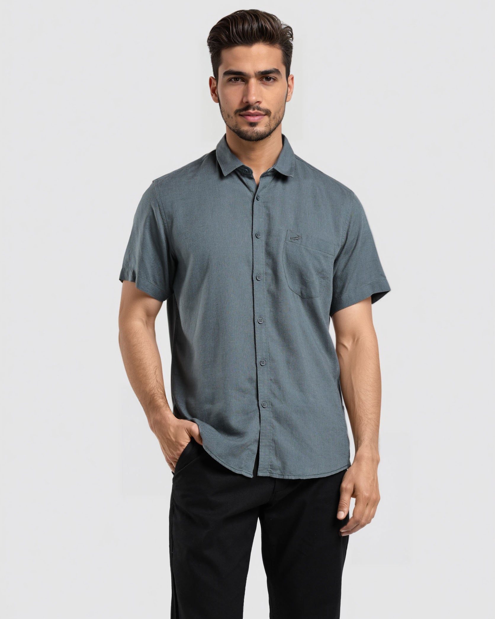 Man wearing a gray button-up shirt and black pants on a light gray background