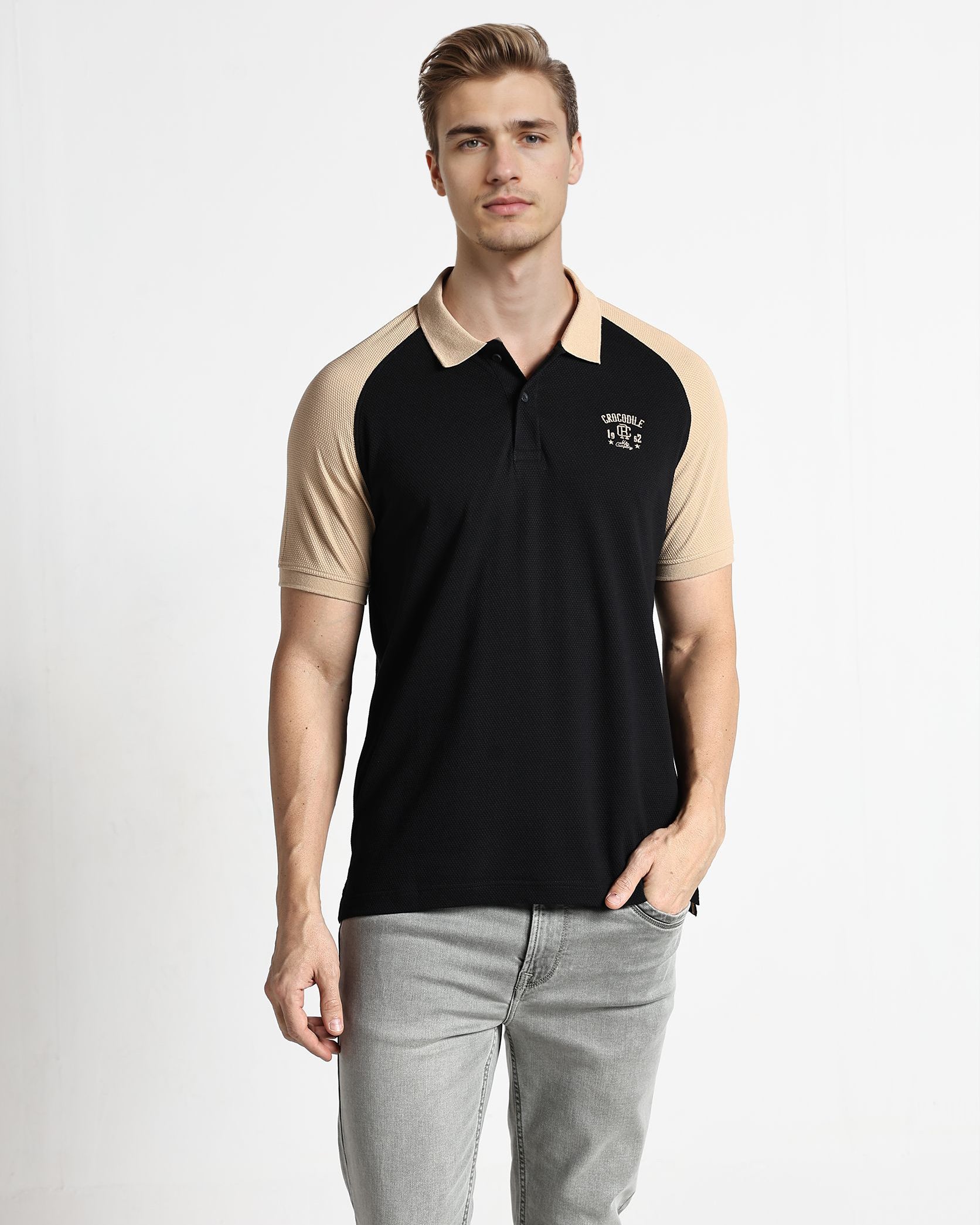 Man wearing a black and beige polo shirt with a logo on a white background