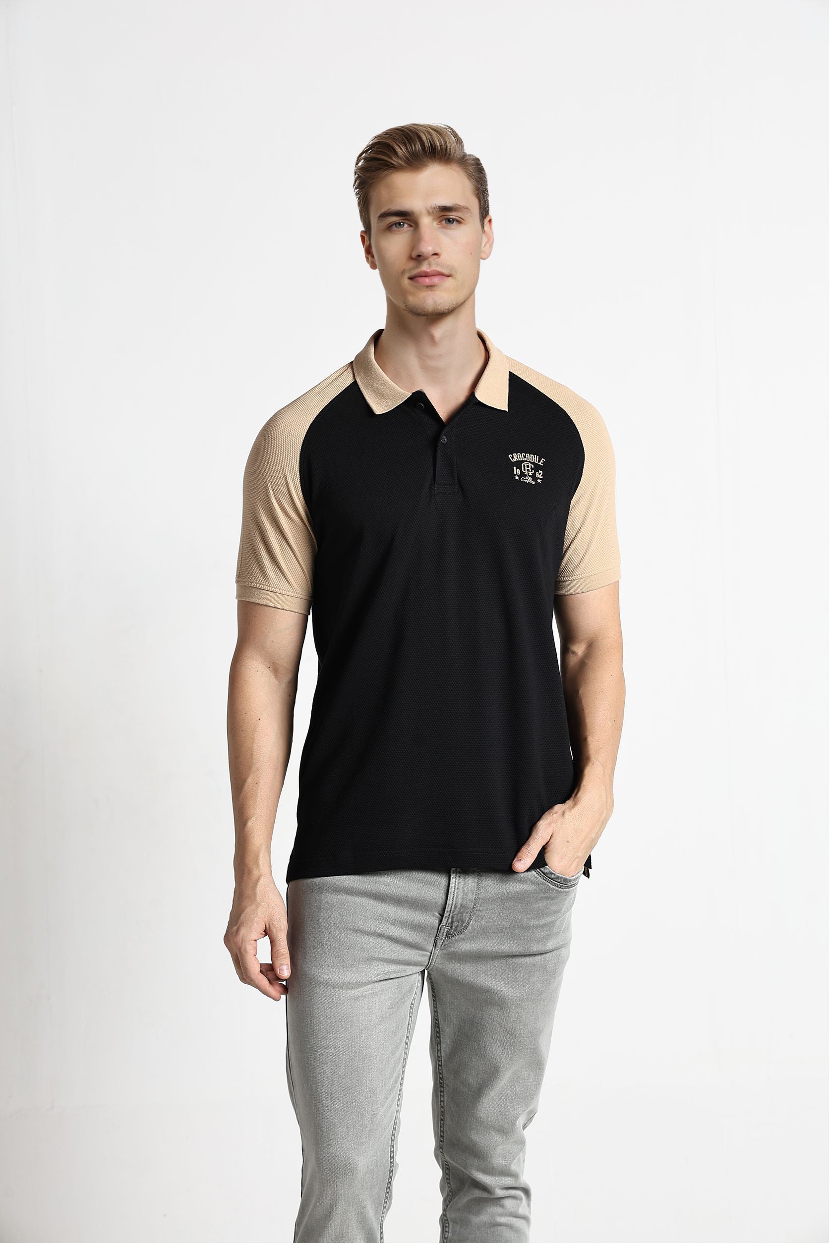 Man wearing a black and beige polo shirt with a logo on a white background