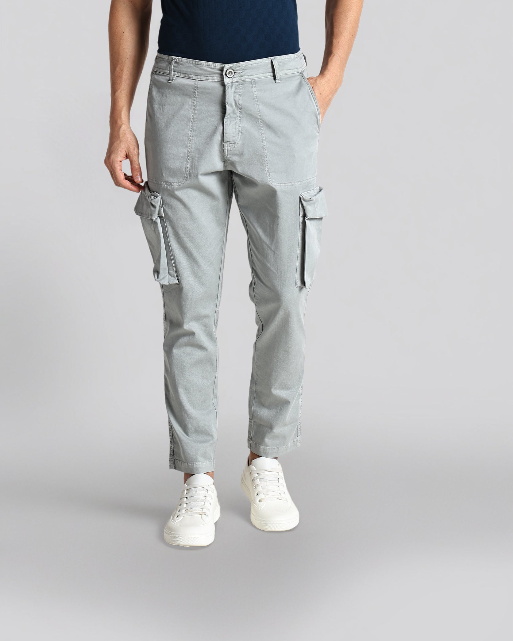 Person wearing gray cargo pants on a plain background