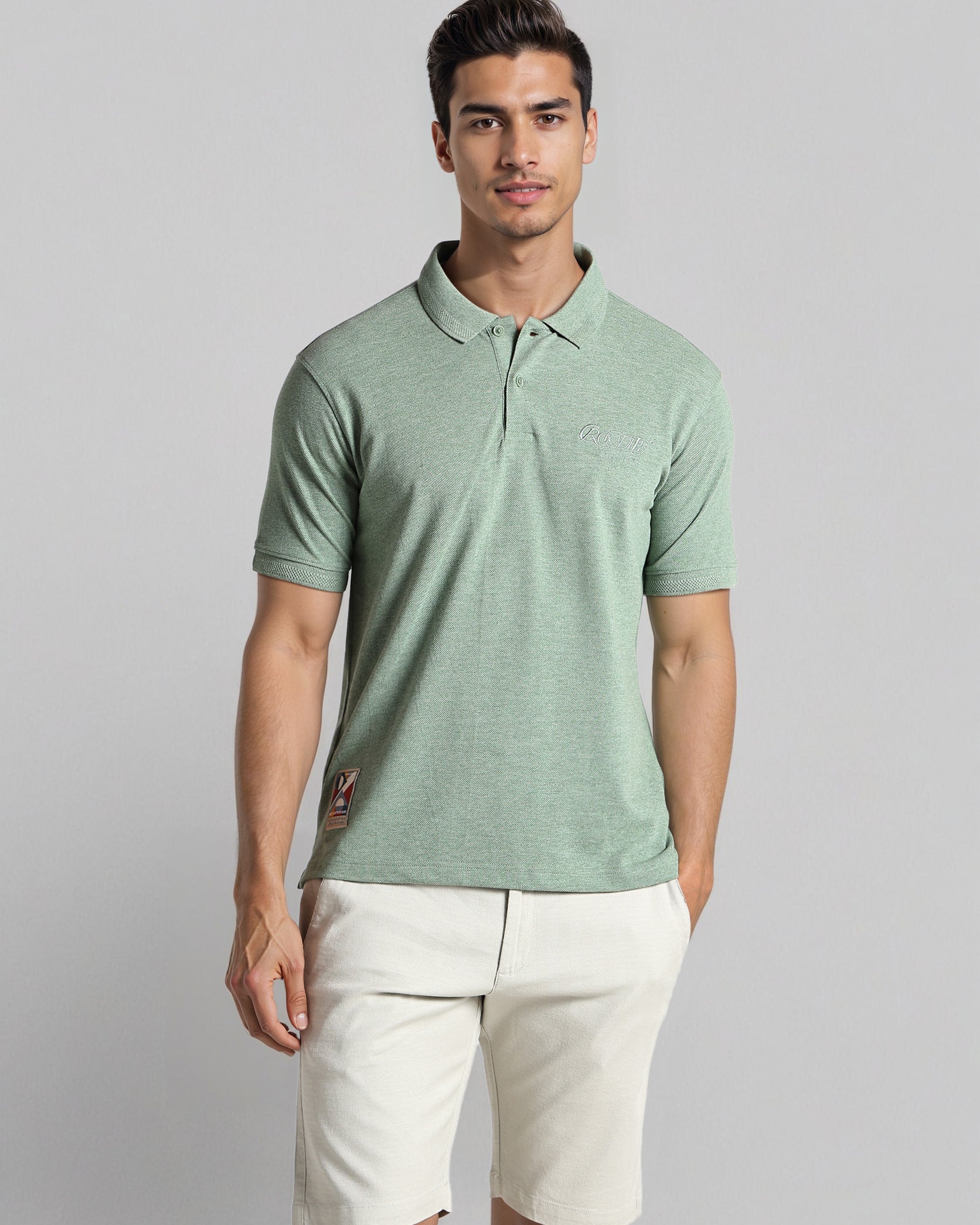 Man wearing a green polo shirt and white shorts on a gray background