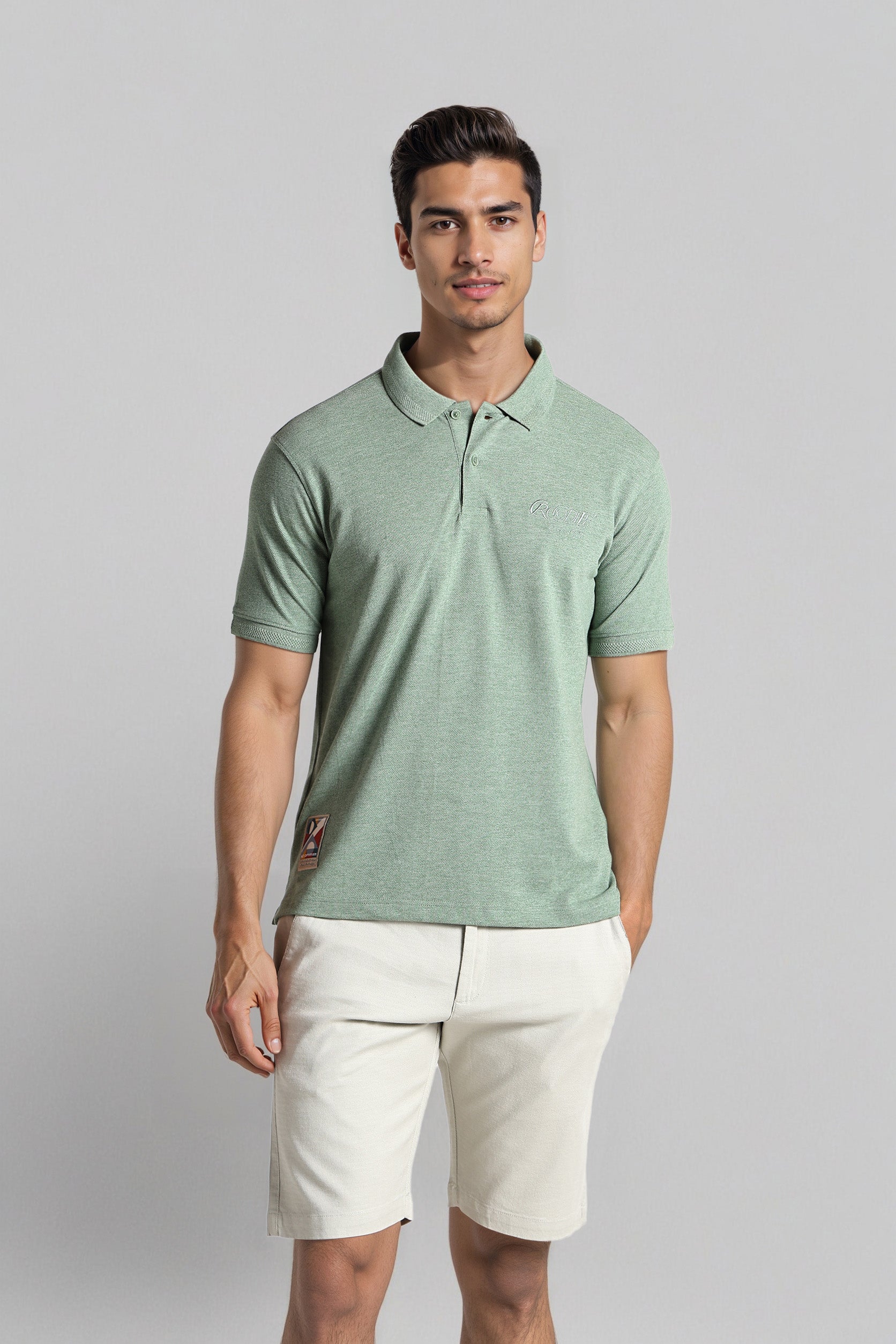 Man wearing a green polo shirt and white shorts on a gray background