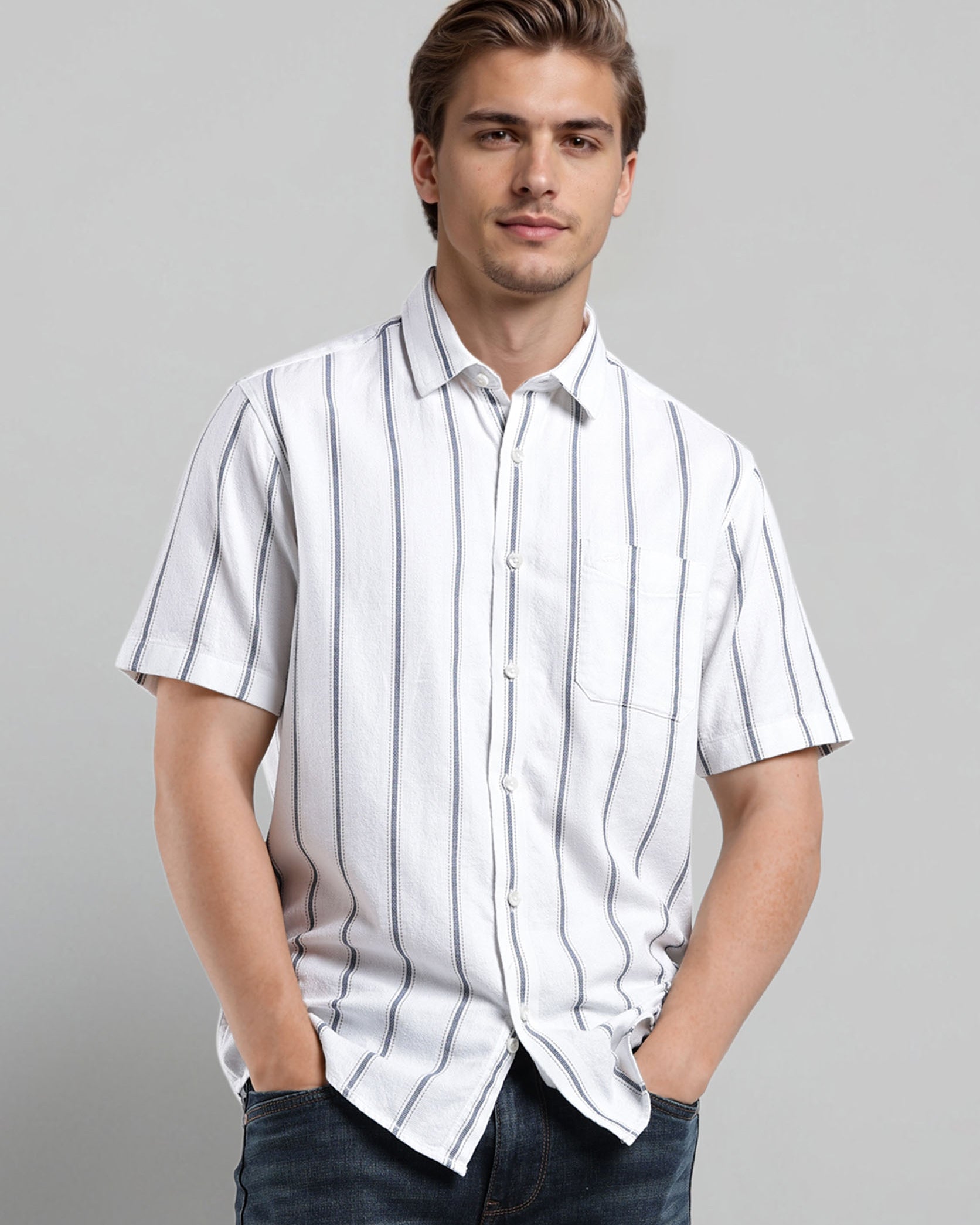 Man wearing a white striped shirt and dark jeans against a gray background