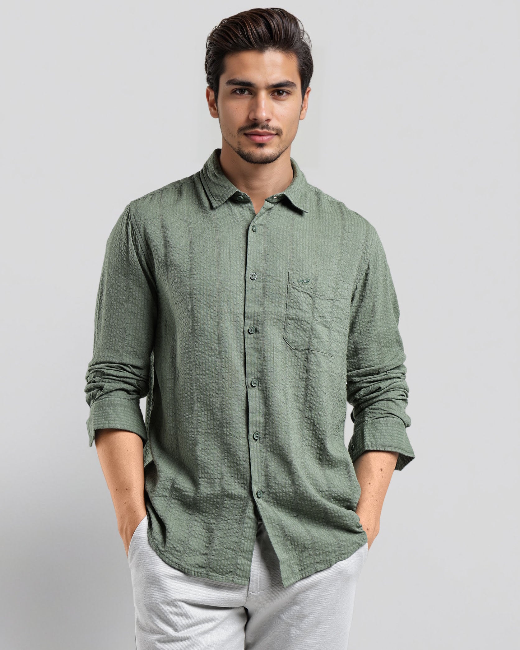 Man wearing a green patterned shirt and white pants on a light gray background